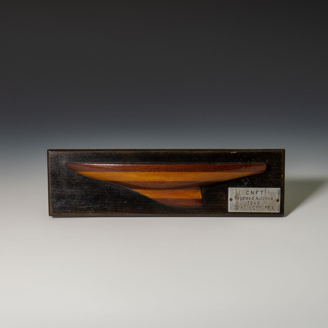 Charming laminated caved wood half hull model, on ebonised back board, dated 1949. The plaque indicates that the model was originally presented as the second prize trophy in a race at the CNFT (Club Nautique de France de Tegel) Regates d’Automne