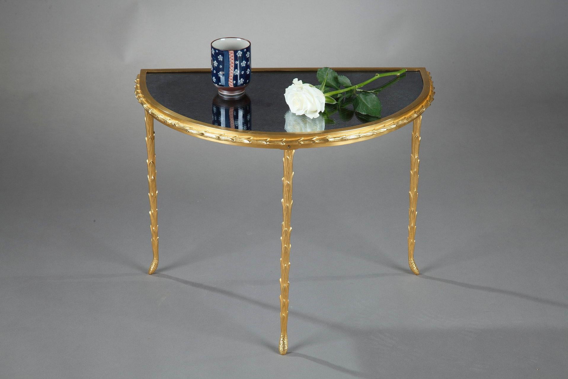Small console of the house Baguès in semicircle with a gilt bronze base. The tray is made of a mirror with an aged black background. The belt and the feet are decorated in a pattern of foliage. Its dates from the 1950s. 

The House of Baguès is a