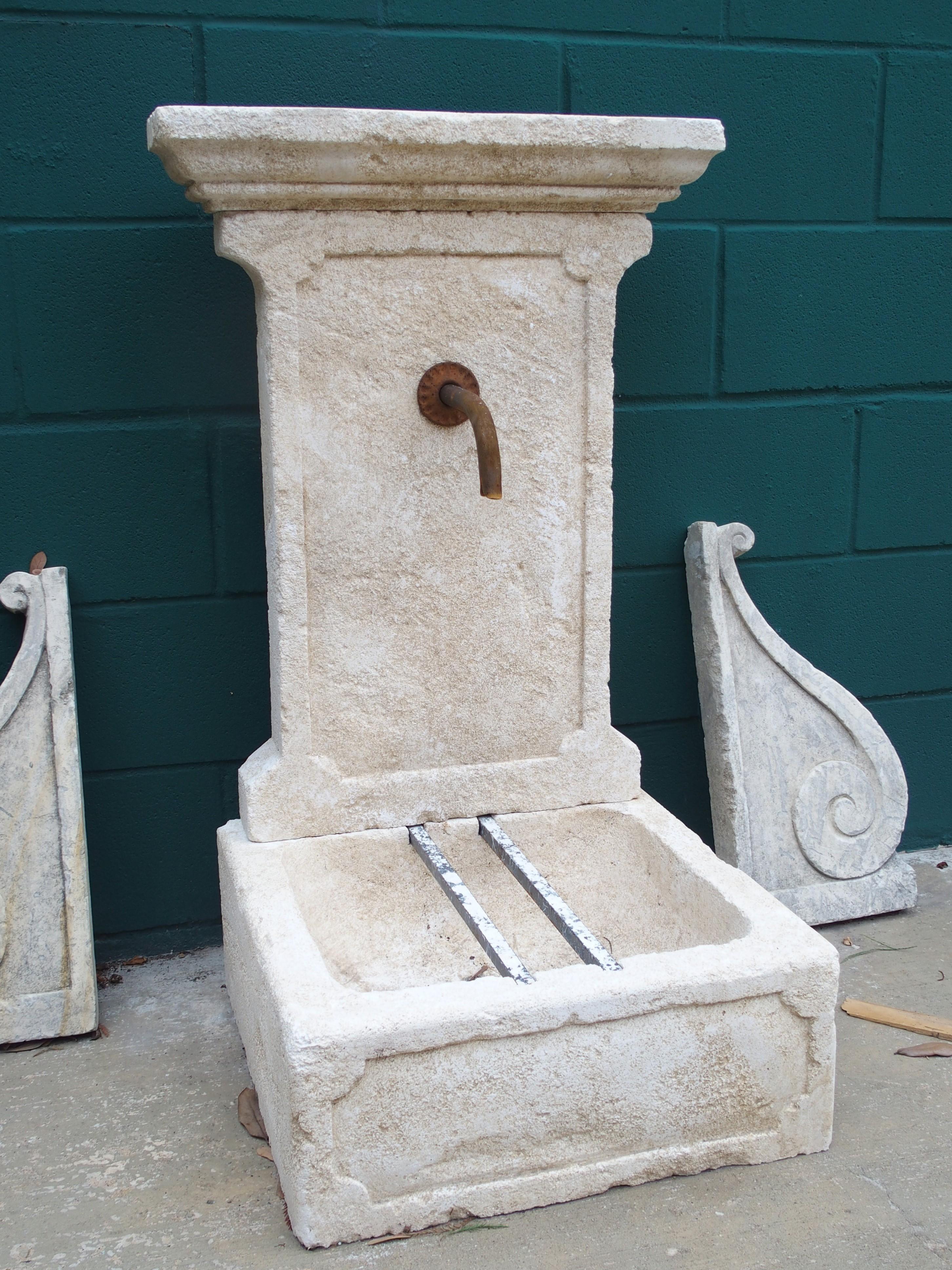 This small wall fountain from Provence, France has been hand-carved in three sections.  A rectangular crown with several layers of molding tops the vertical back wall which is adorned with thick molding and protruding corners.  It has an in-carved