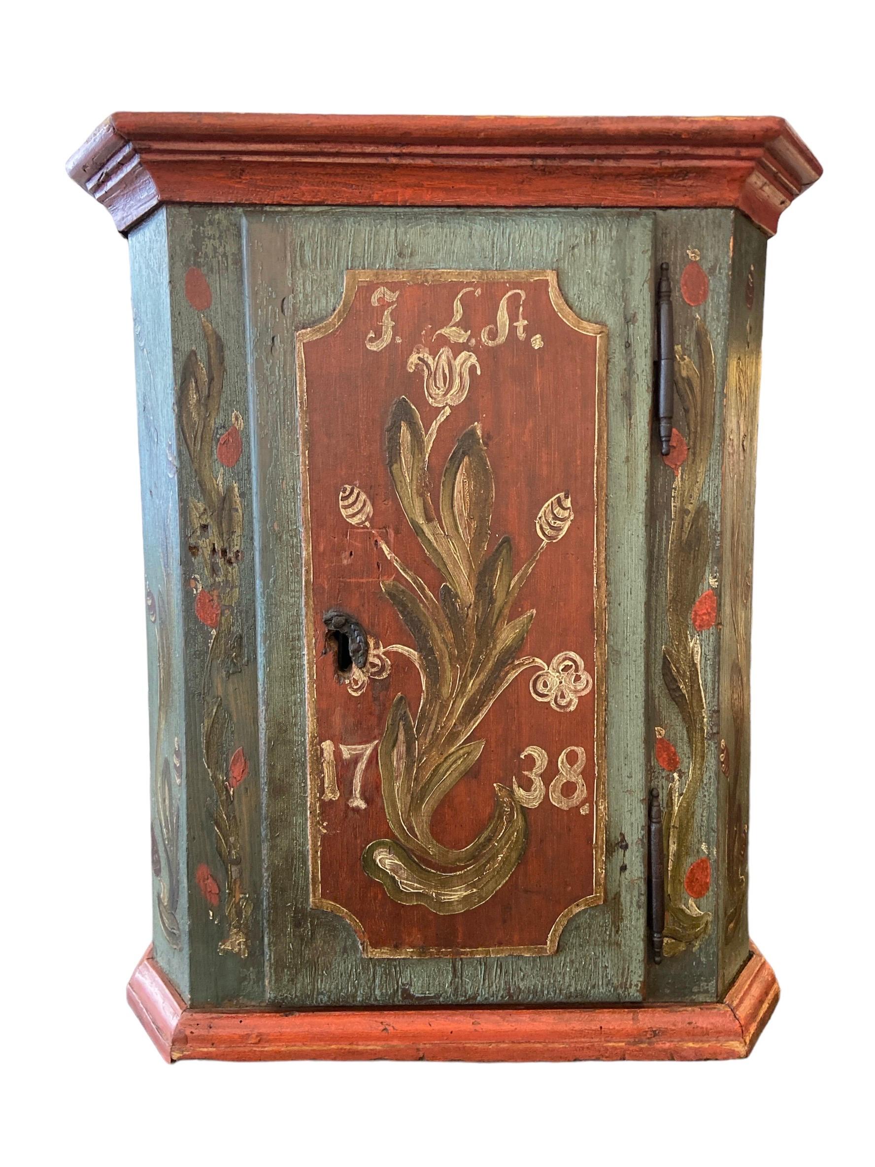 Pequeño  armario con 1 puerta. Pintada a mano con motivos florales decorativos.
Fechada en 1738. El interior tiene 2 estantes, falta un cajón pequeño.