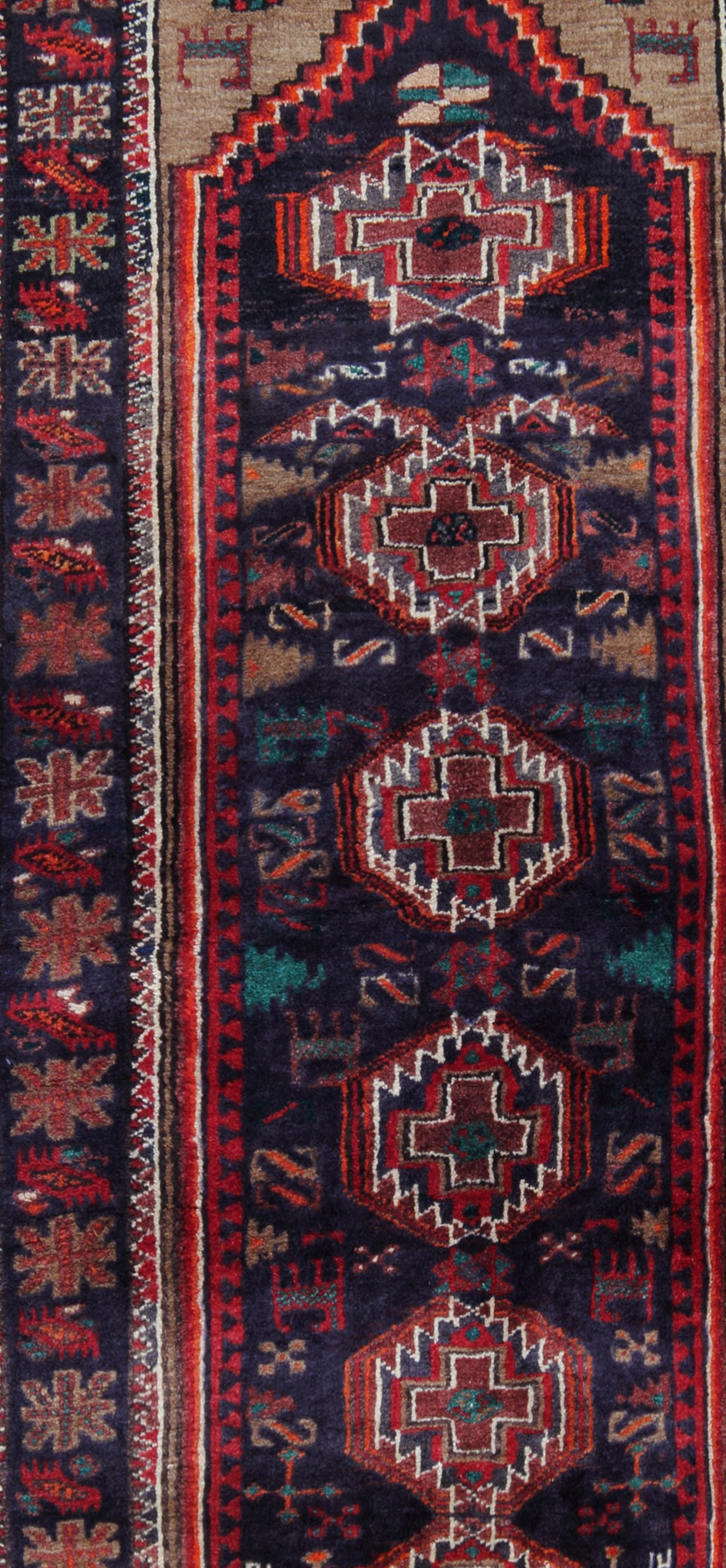 This vintage carpet was constructed by hand with fine organic materials. Woven with a traditional design and colour palette. Tribal medallions have been woven through the centre in red, brown and white accents on deep blue background, with a rich