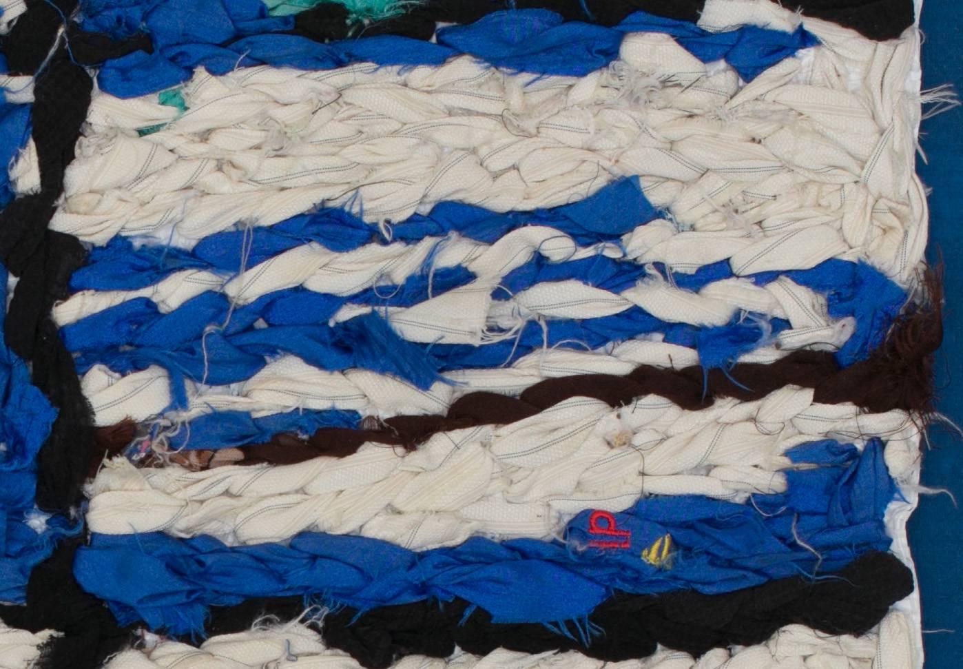 Blue tapestry made by Berber women from the Atlas Mountains.
This unique and vintage work is made of pieces of clothing embroidered on cereal plastic recovery bags. 
It becomes the fruit of imagination and intuition without any reference.