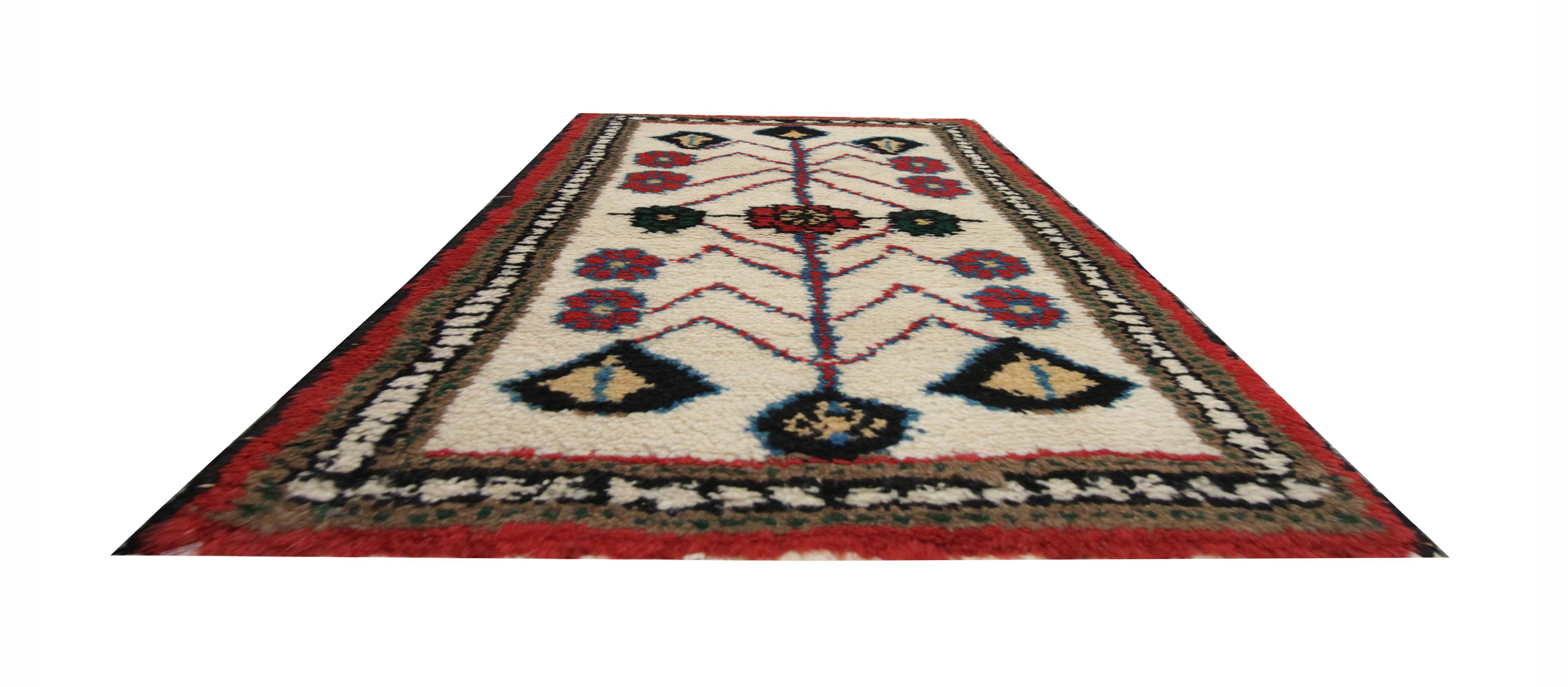 This wool carpet has been woven with a simple tribal design, symmetrically designed with a tribal pattern. Constructed with a simple colour palette of red, blue, and green accents with a cream/ivory background. Both the colour and oriental design in