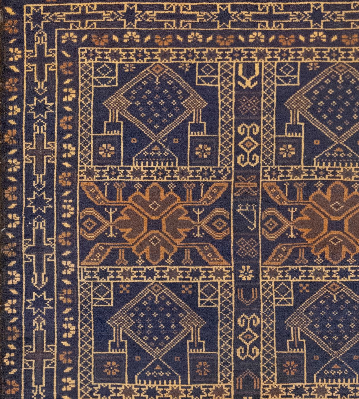 Ce petit tapis baloutche tissé à la main présente un champ central avec deux colonnes de cinq panneaux bleus nuancés contenant une alternance de losanges crochetés centraux brun-renard et de losanges en forme de diamant flanqués de petits motifs