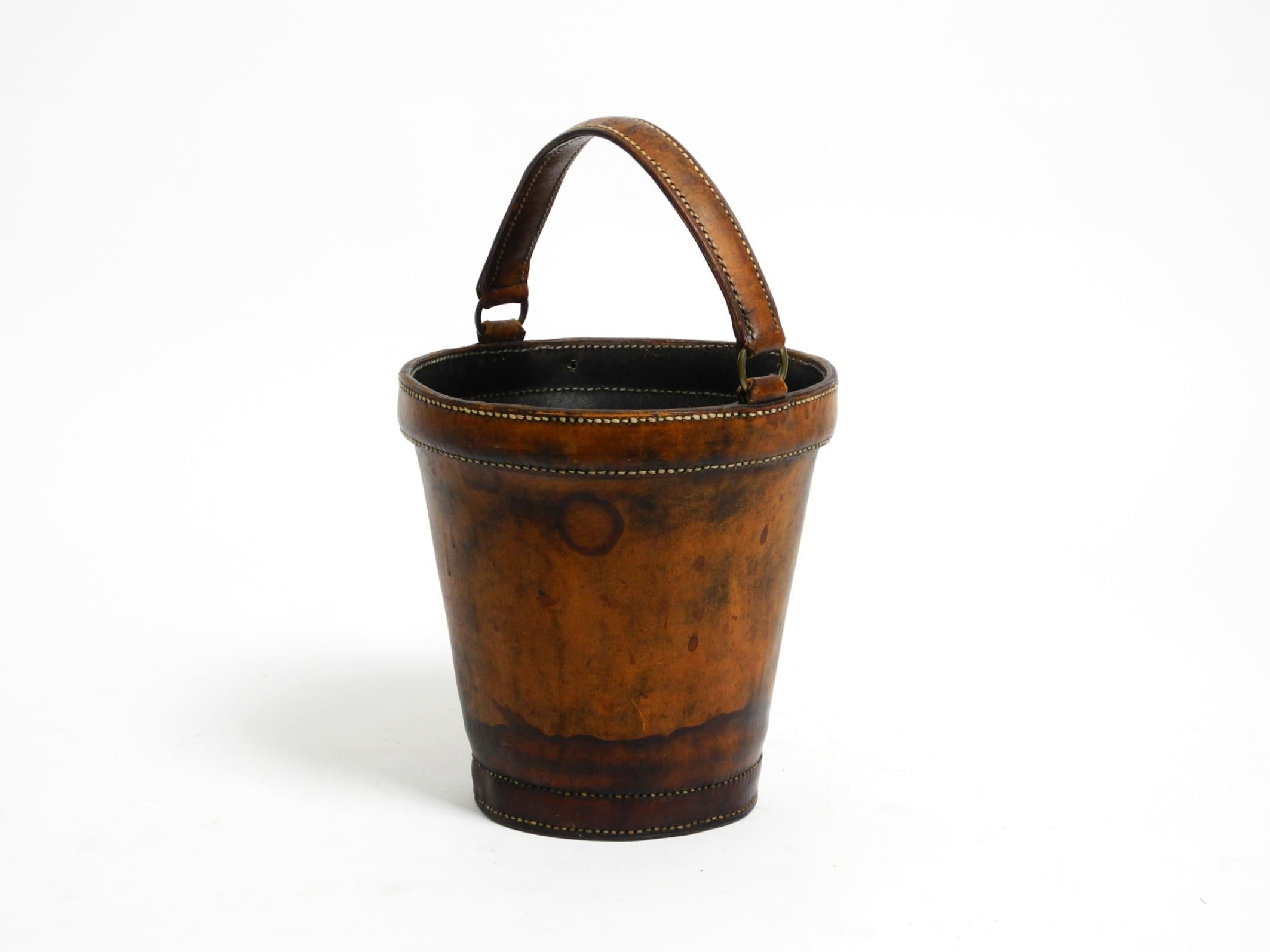Small, heavy mid-century modern paper basket made of sturdy, thick brown cowhide.
Can also be used for other purposes.
Very stable and robust thanks to the thick leather. Well-greased. Black interior.
No damage, no tears, or deformation. All seams