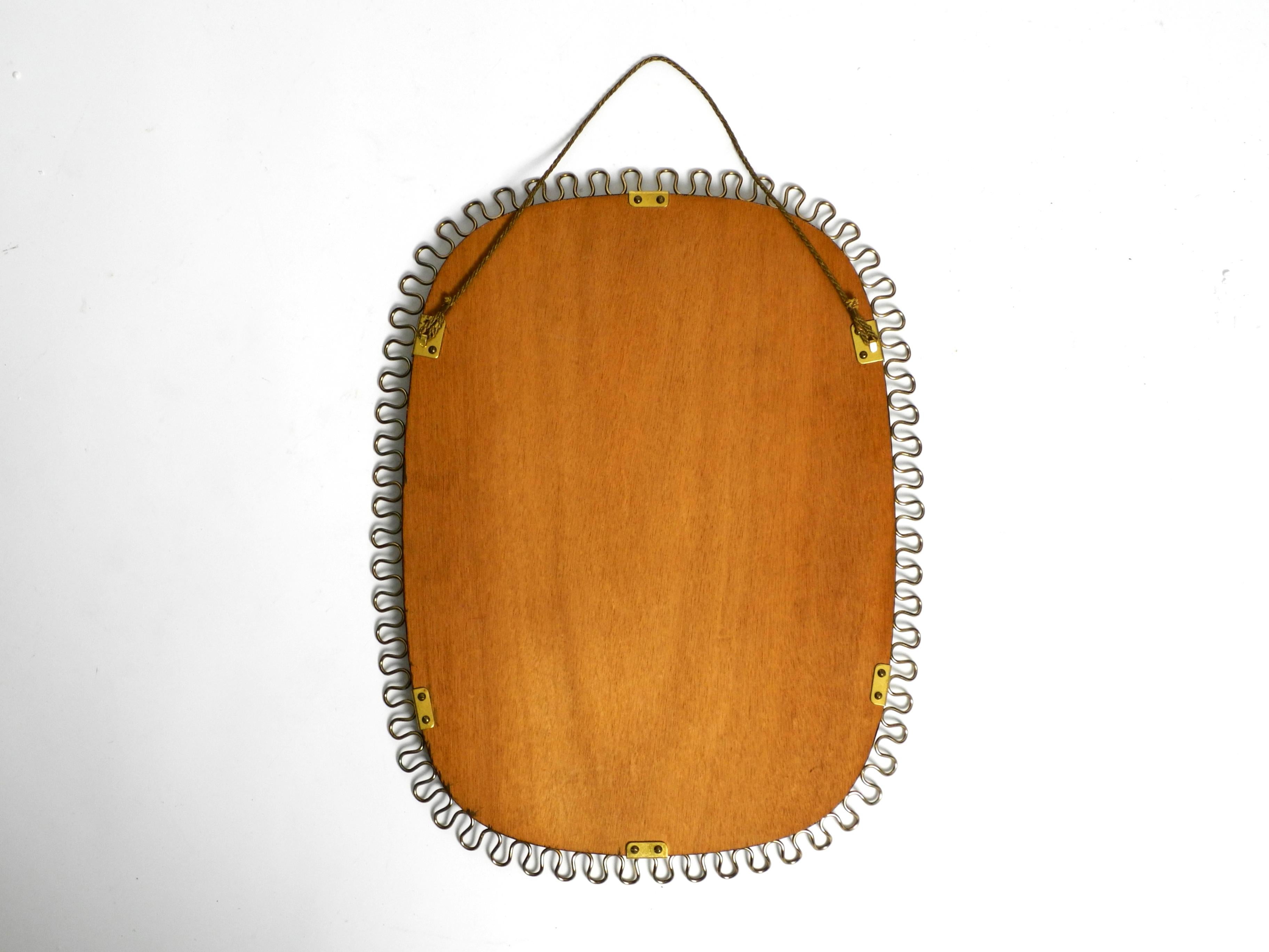 Small, heavy Mid Century wall mirror with a frame with gold colored metal loops 3
