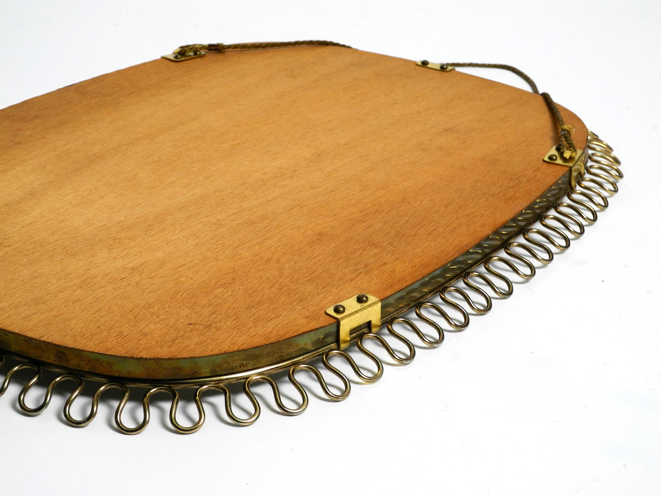 Small, heavy Mid Century wall mirror with a frame with gold colored metal loops For Sale 6