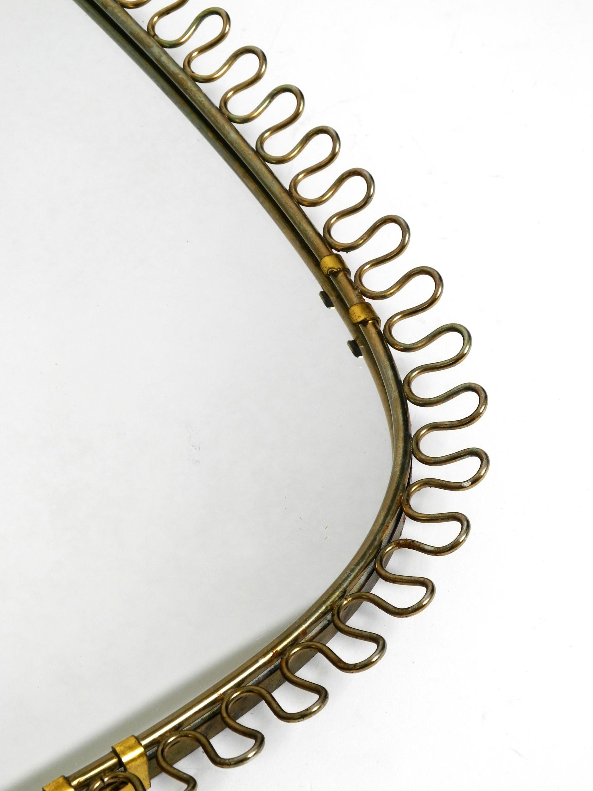 Small, heavy Mid Century wall mirror with a frame with gold colored metal loops 8