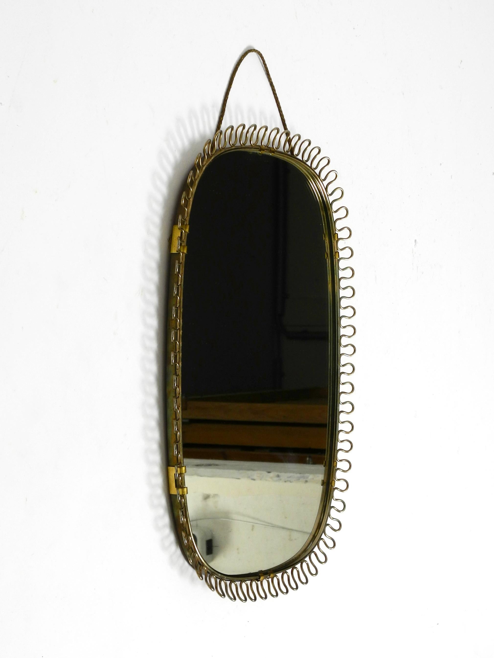 Small, heavy Mid Century wall mirror with a frame with gold colored metal loops For Sale 11
