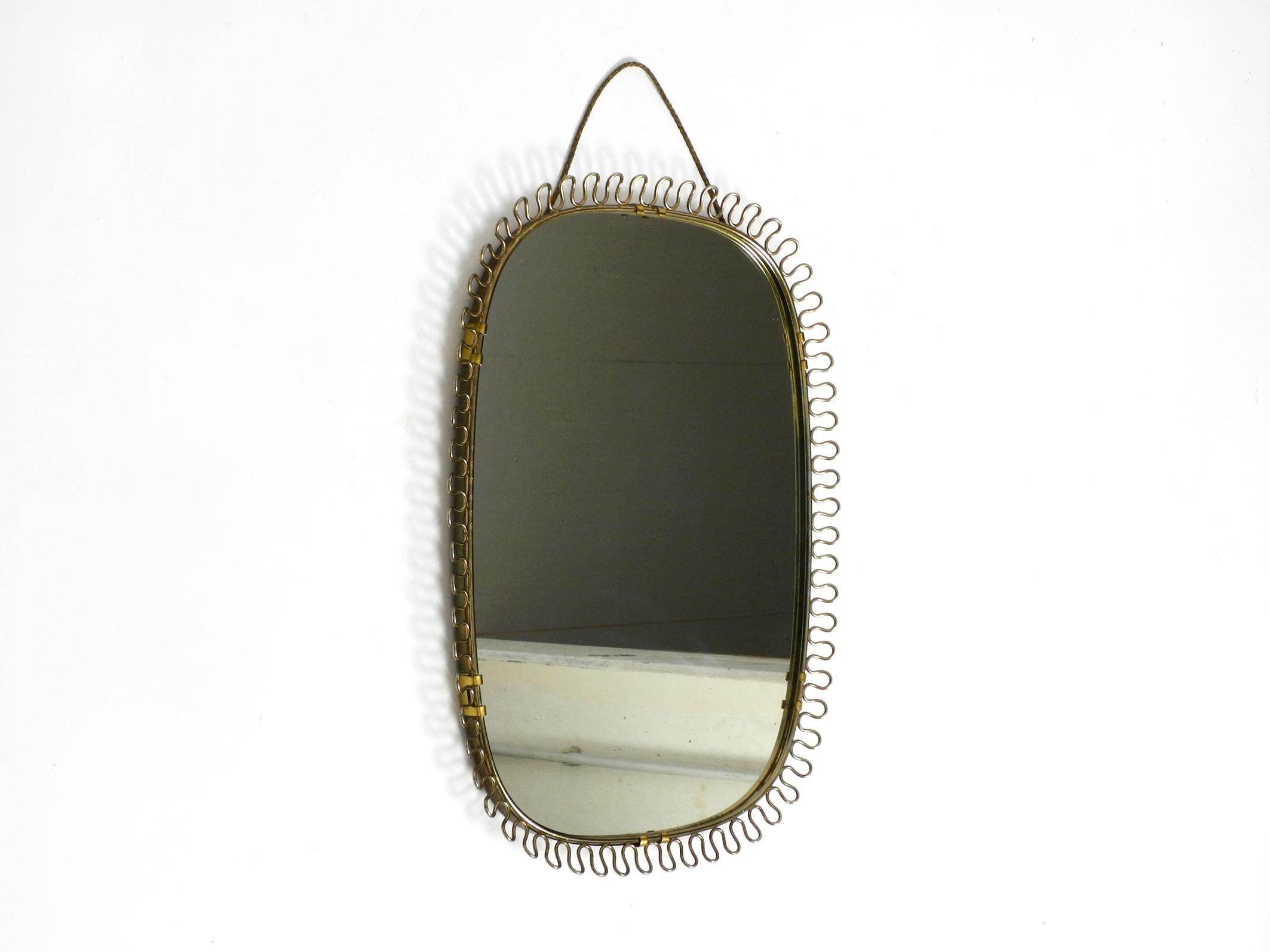 Beautiful small heavy original Mid Century metal wall mirror.
Frame is made of heavy metal in brass color with a great design with loops.
Heavy and solidly built, with original hanging rope in gold.
No damage to the entire mirror.
Light patina and