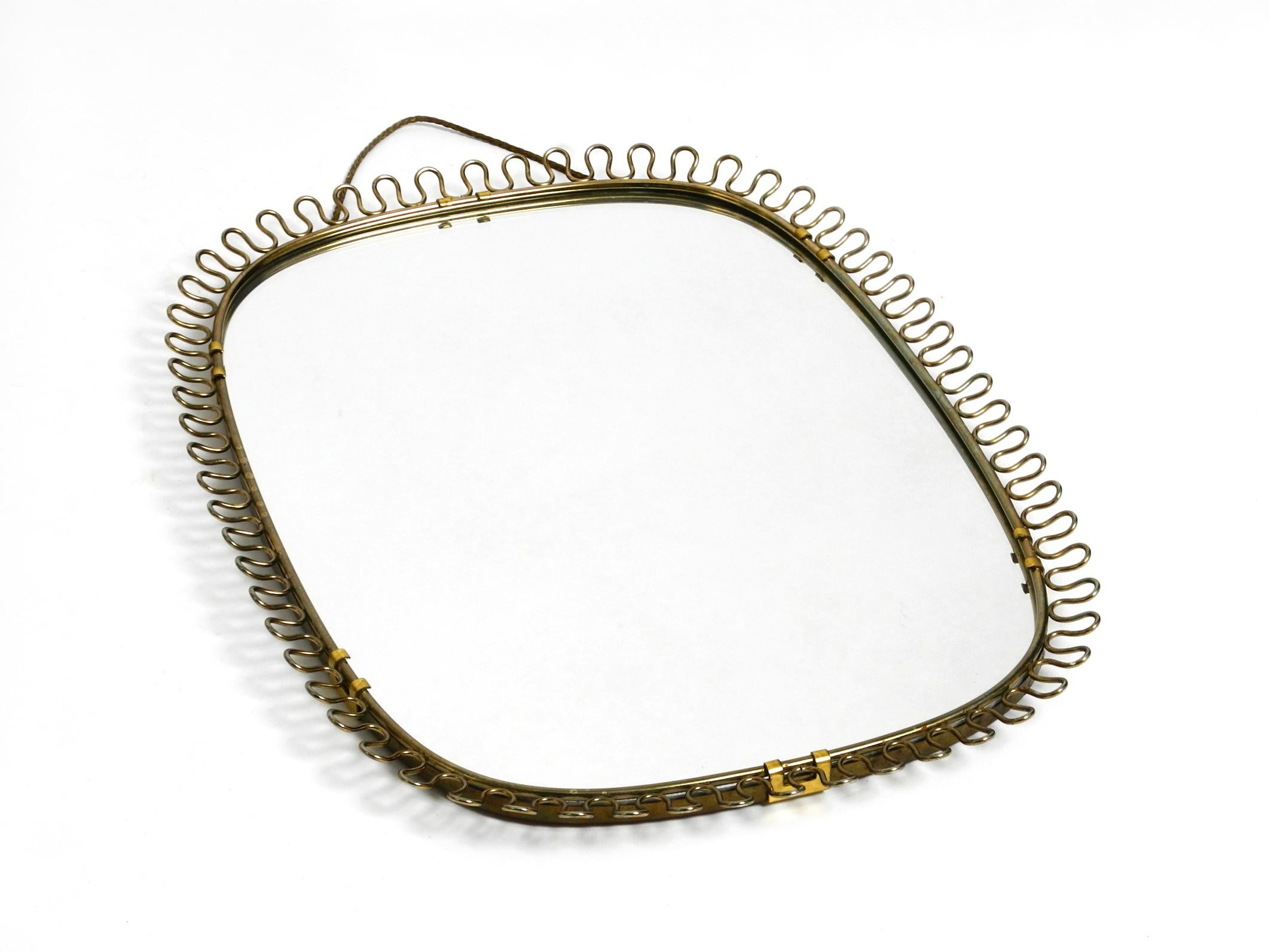 Mid-Century Modern Small, heavy Mid Century wall mirror with a frame with gold colored metal loops For Sale