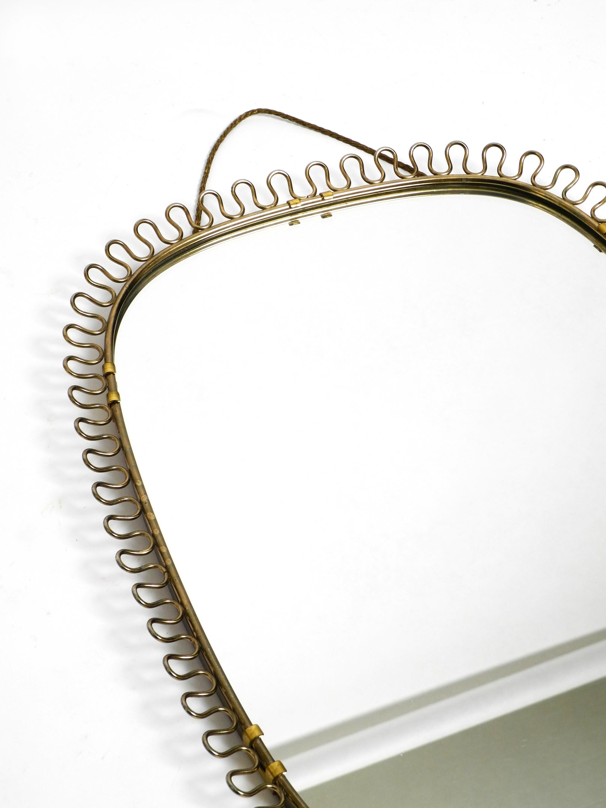 European Small, heavy Mid Century wall mirror with a frame with gold colored metal loops For Sale