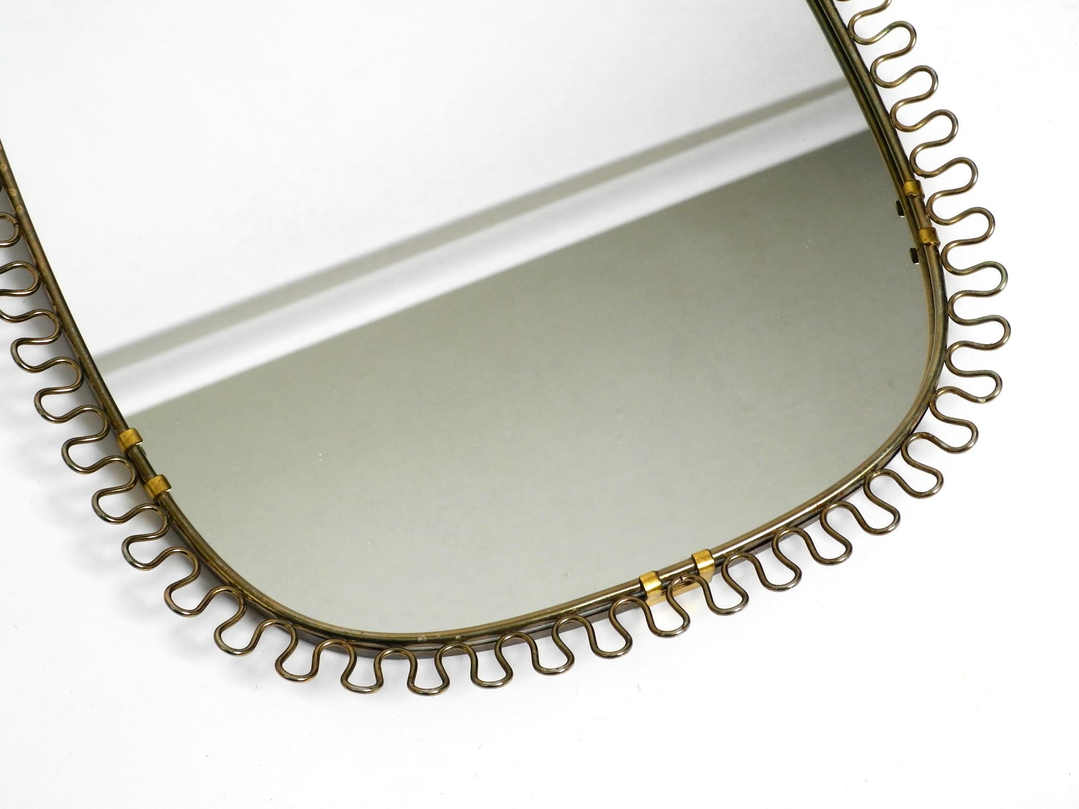 Small, heavy Mid Century wall mirror with a frame with gold colored metal loops In Good Condition In München, DE