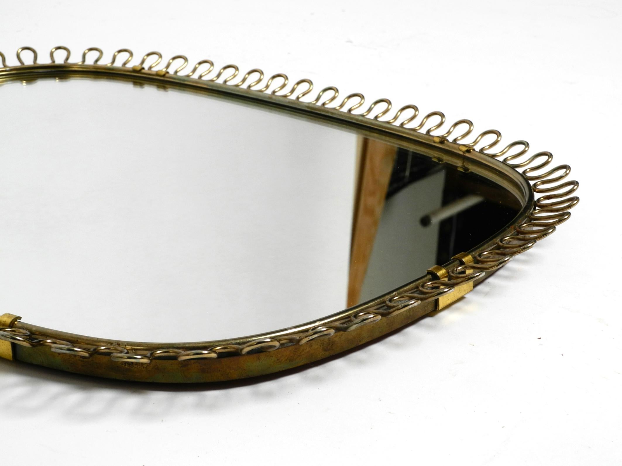 Mid-20th Century Small, heavy Mid Century wall mirror with a frame with gold colored metal loops For Sale