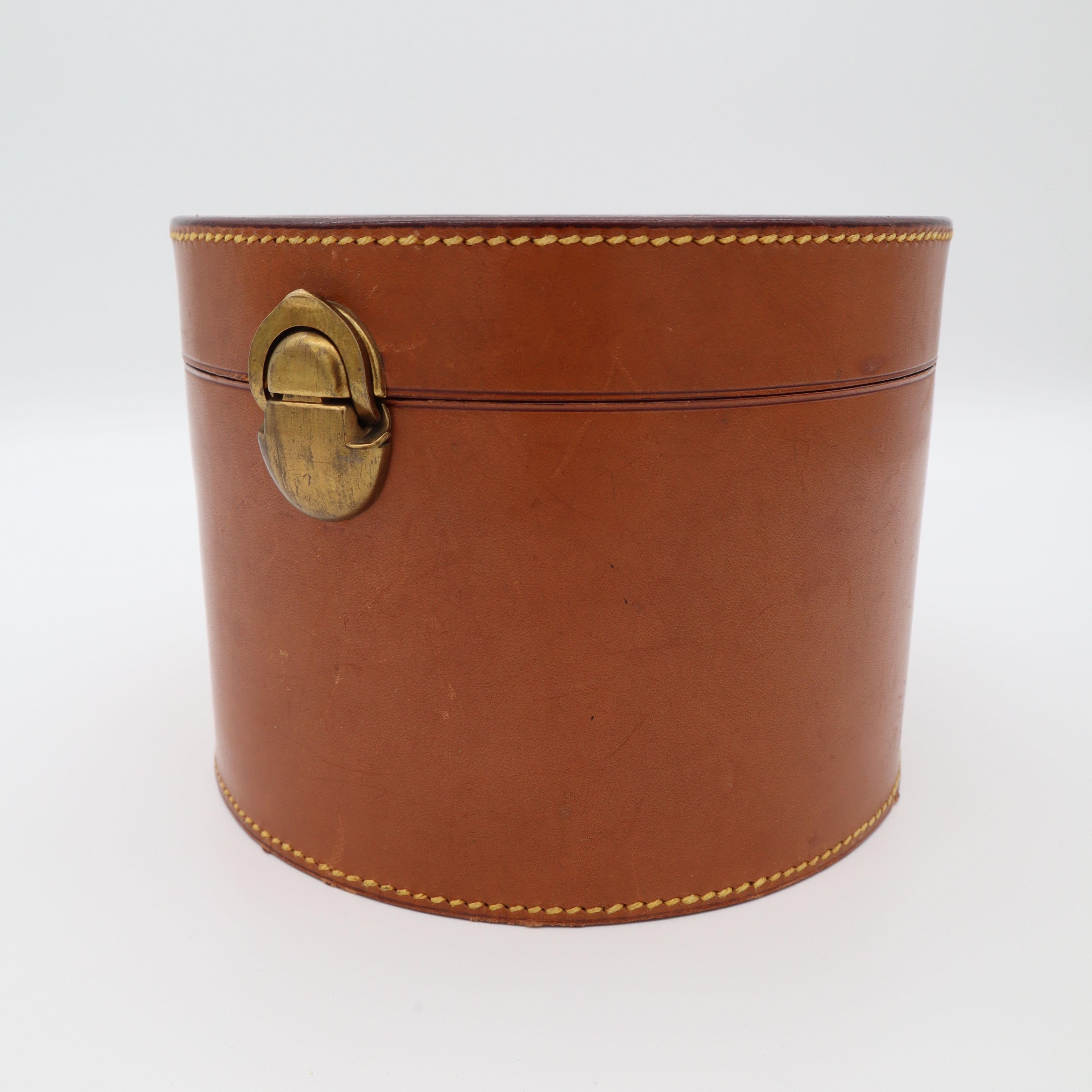 Small leather box for fascinators or silk-scarfs for storage and travel.
Beautiful hand-sewn and hand-crafted.
It has a brass closure.

Manufactured in Prague in the name of Ernest Hofmann for K&K, see underside emblem of the Box.