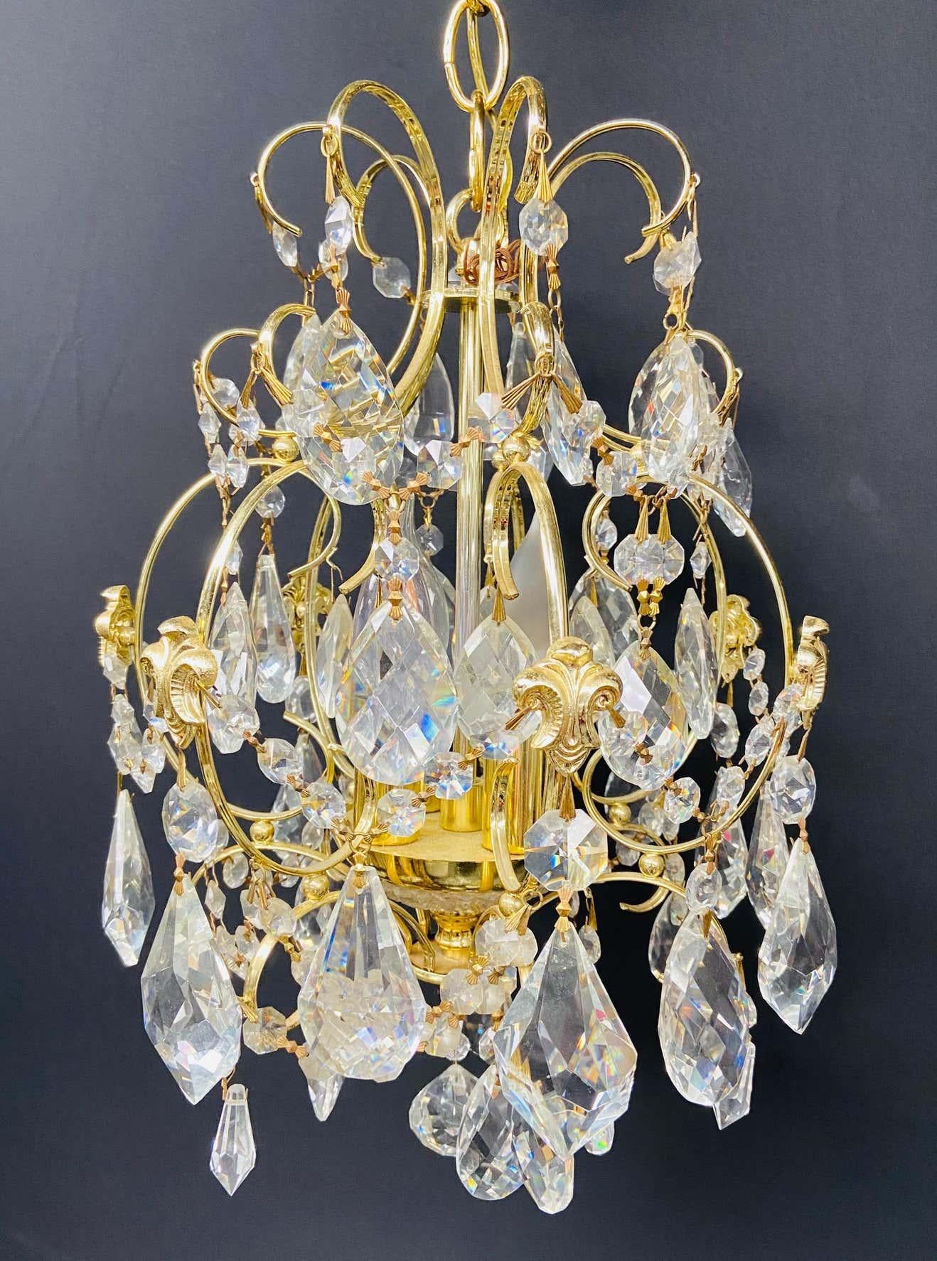 A beautiful cascading gilt brass frame and crystal chandelier in the Hollywood Regency style. The chandelier is in excellent condition and would look gorgeous in a foyer or a small living room.

Dimensions: 15