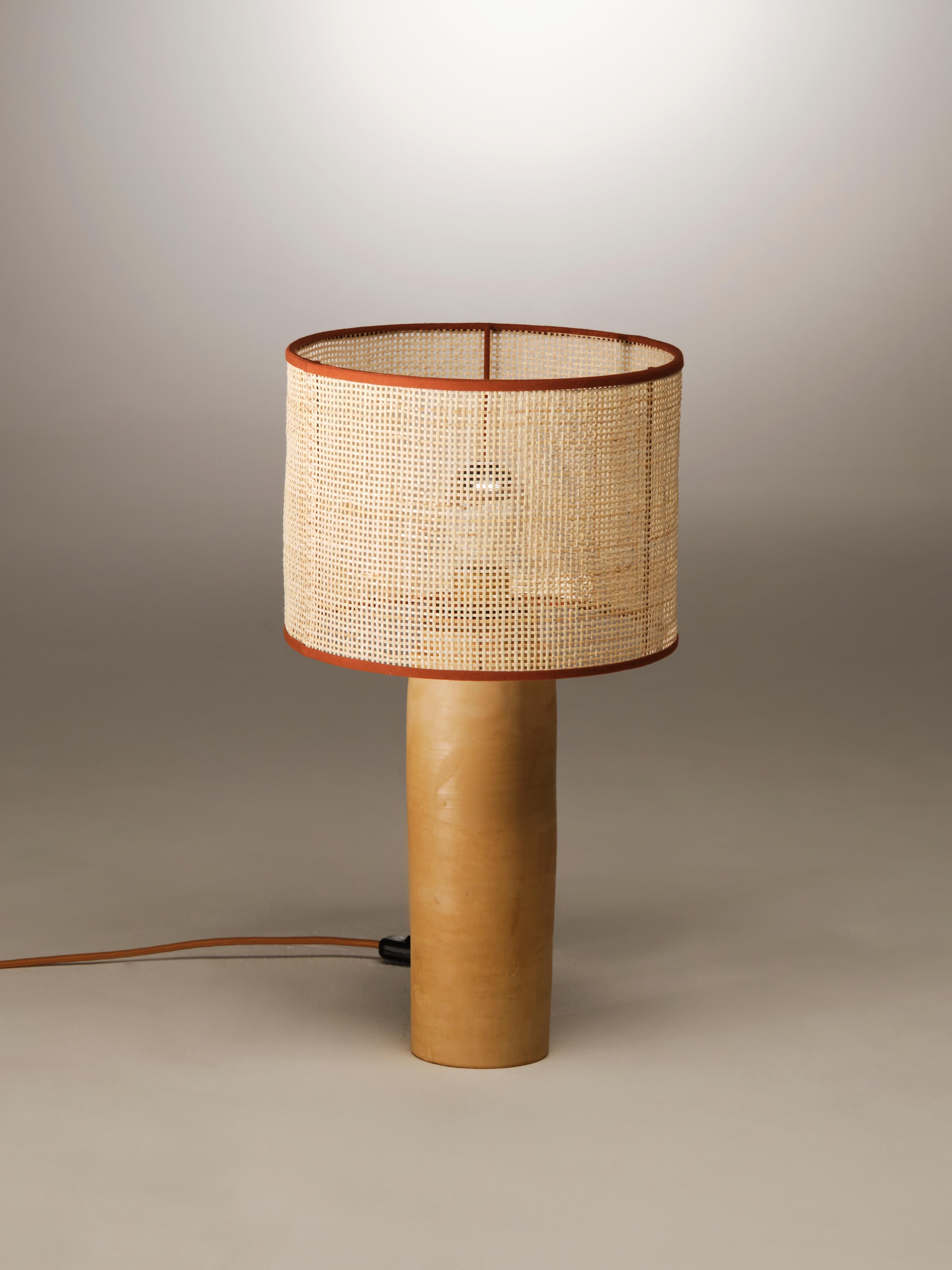 Small II Sonora Rattan Table Lamp by NASSI
Dimensions: W 27 x D 27 x H 49 cm. 
Materials: Lampshade: coated iron, Natural rattan, cotton trimmings
Base: wood-fired clay with beeswax finish.
Weight 1,6 kg

About: An established part of the handmade