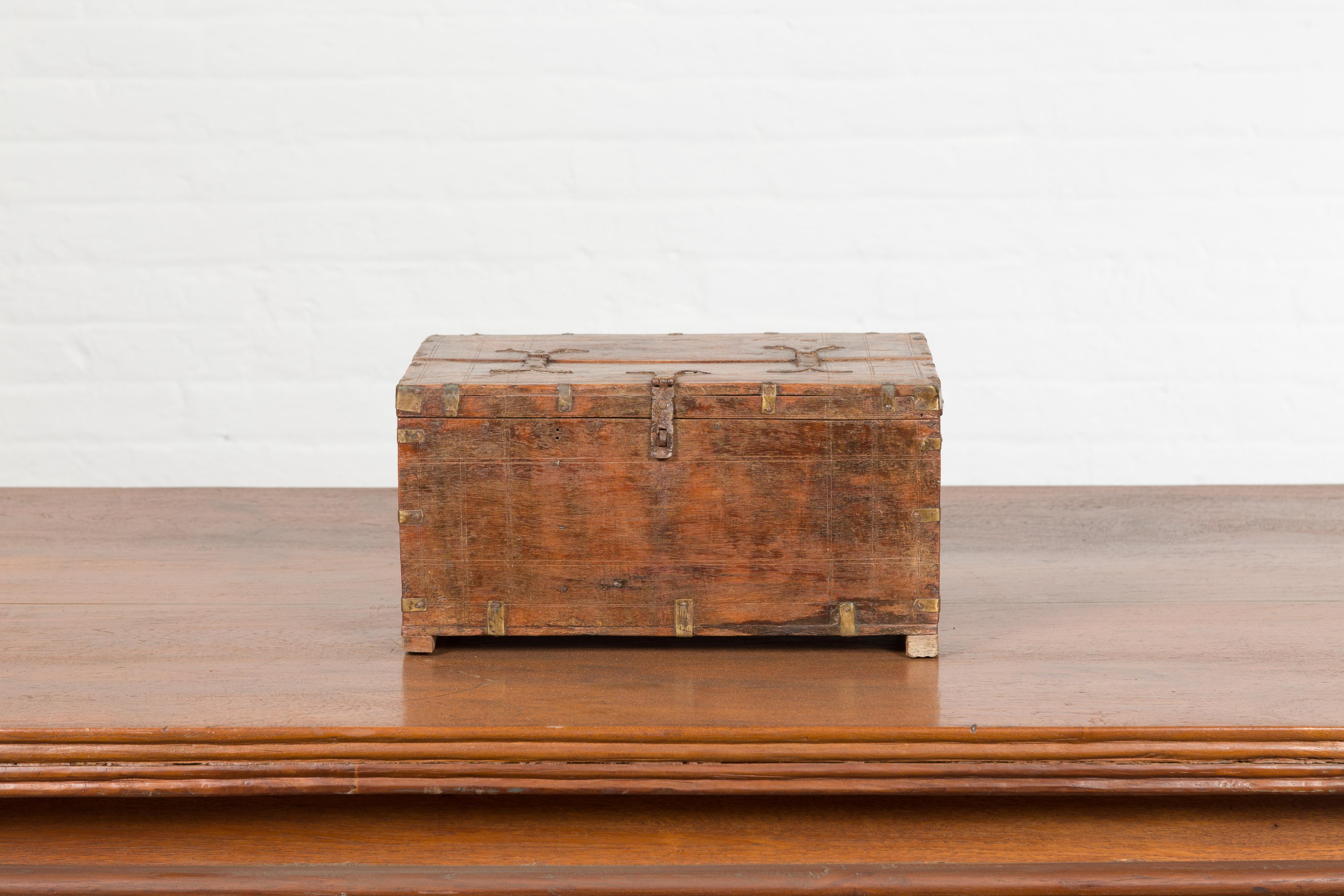 Une petite boîte indienne antique du 19ème siècle, avec des détails en laiton et un intérieur compartimenté. Créée en Inde au XIXe siècle, cette petite boîte en bois présente un couvercle rectangulaire s'ouvrant à moitié pour révéler un intérieur