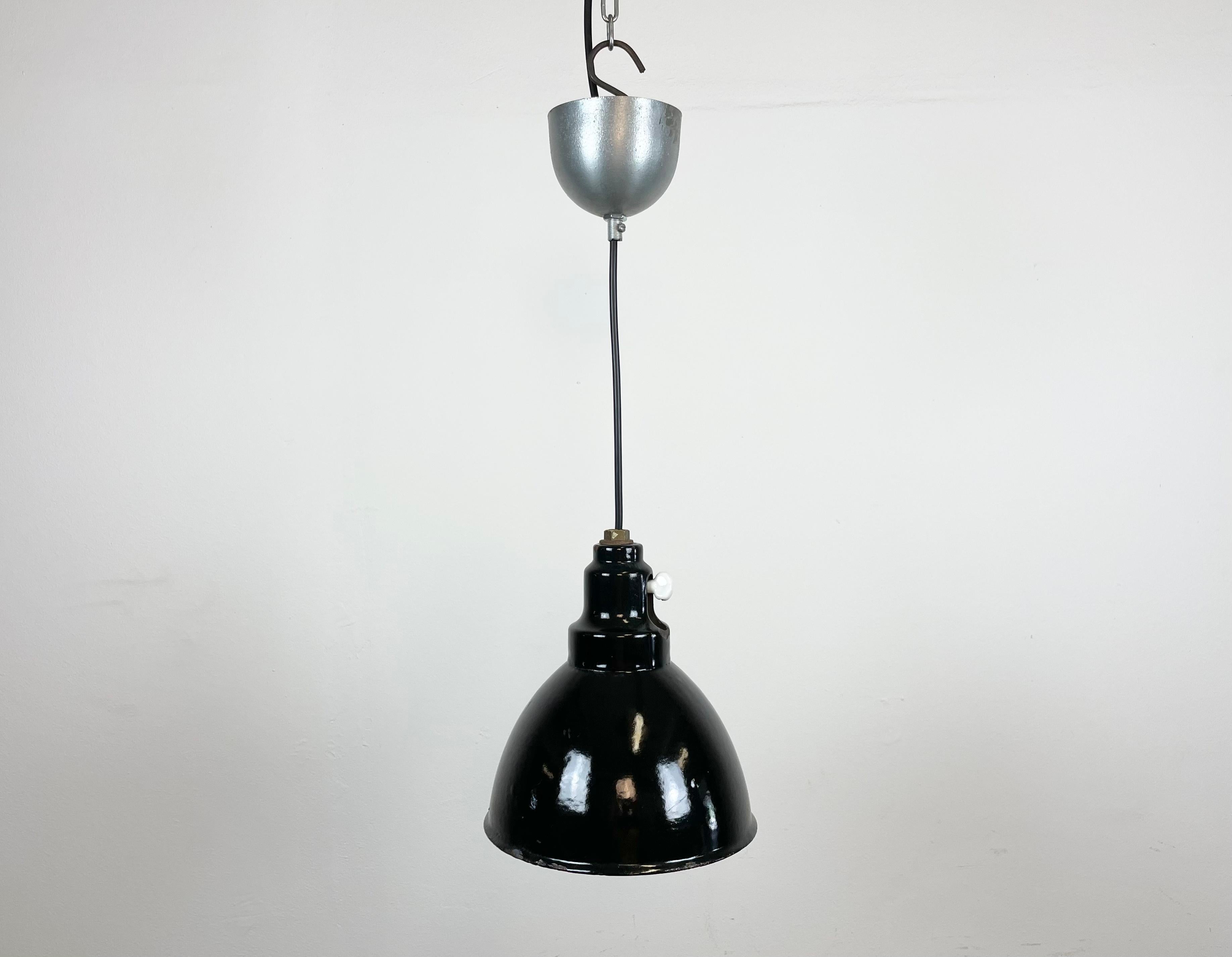 Industrial black enamel pendant light made in former Czechosloivakia during the 1950s. White enamel inside the shade. Metal celing canopy. The original socket with switch requires E 27/ E 26 light bulbs. New wire. Fully functional. The weight of the
