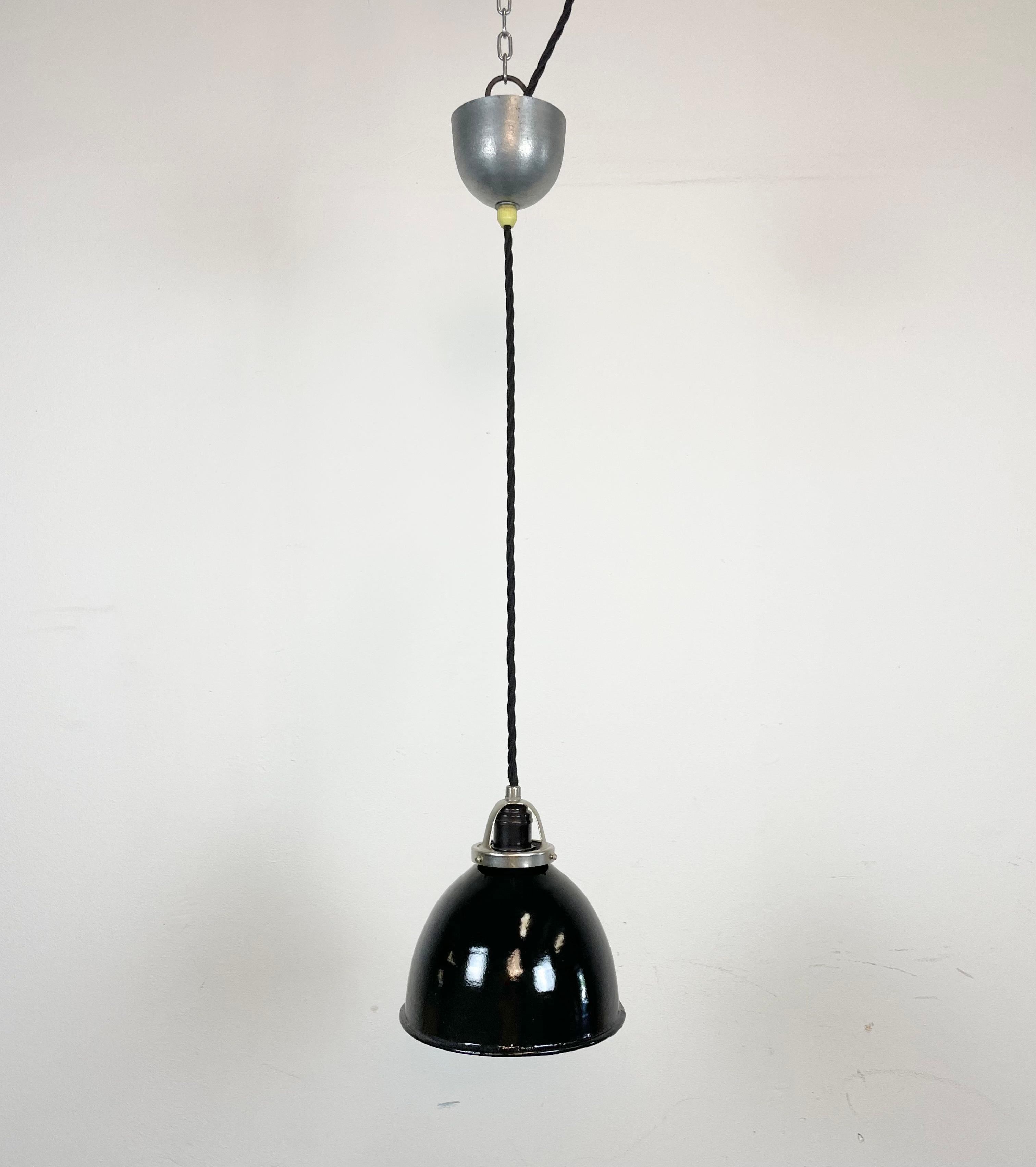 Industrial black enamel pendant light made in former Czechosloivakia during the 1950s. White enamel inside the shade. Metal celing canopy. The socket requires E 27/ E 26 light bulbs. New wire. Fully functional. The weight of the lamp is 0,5
