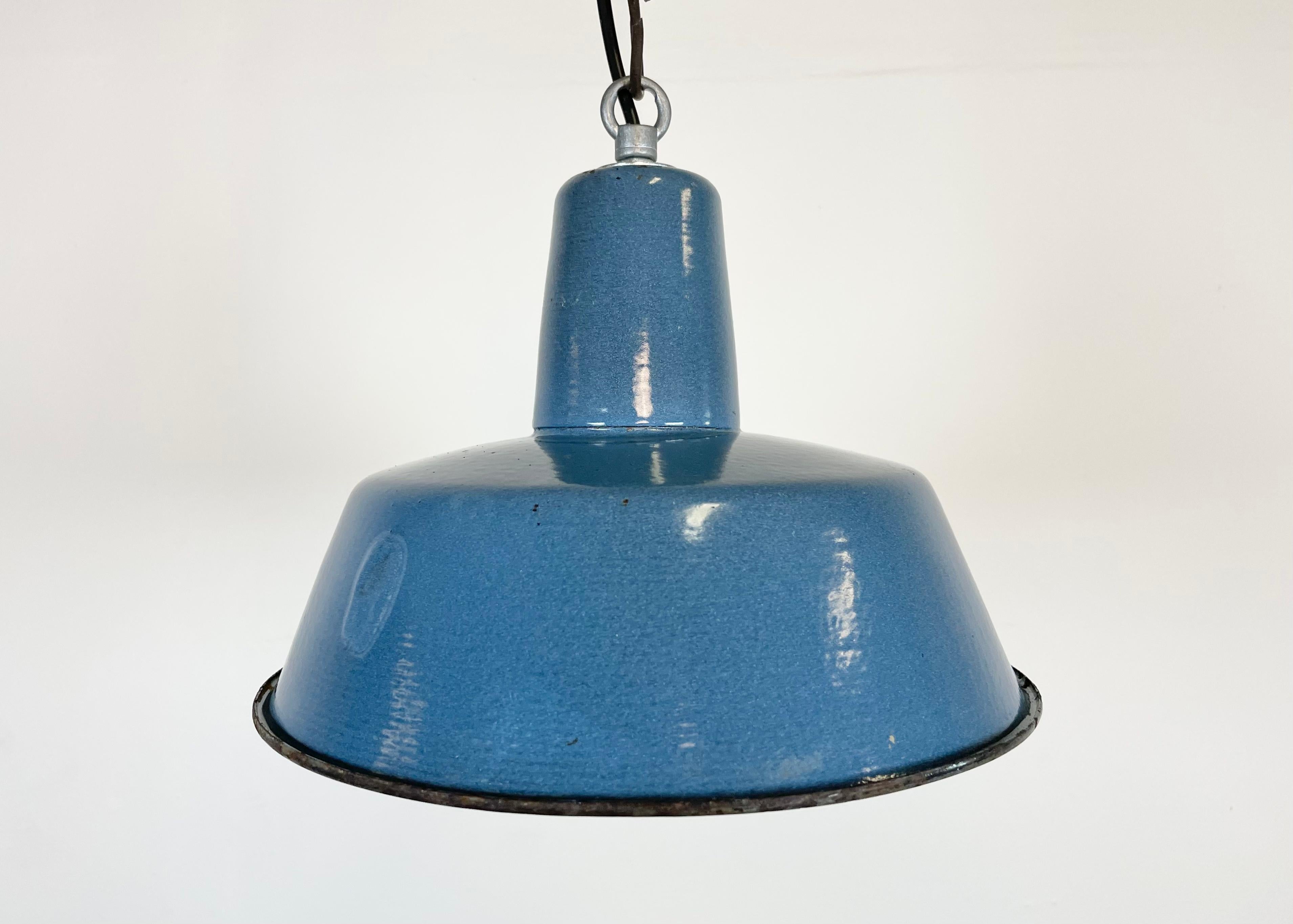 Industrial blue enamel pendant light made in Poland during the 1960s. White enamel inside the shade. Iron top. The porcelain socket requires E 27/ E 26 light bulbs. New wire. Fully functional. The weight of the lamp is 1 kg.