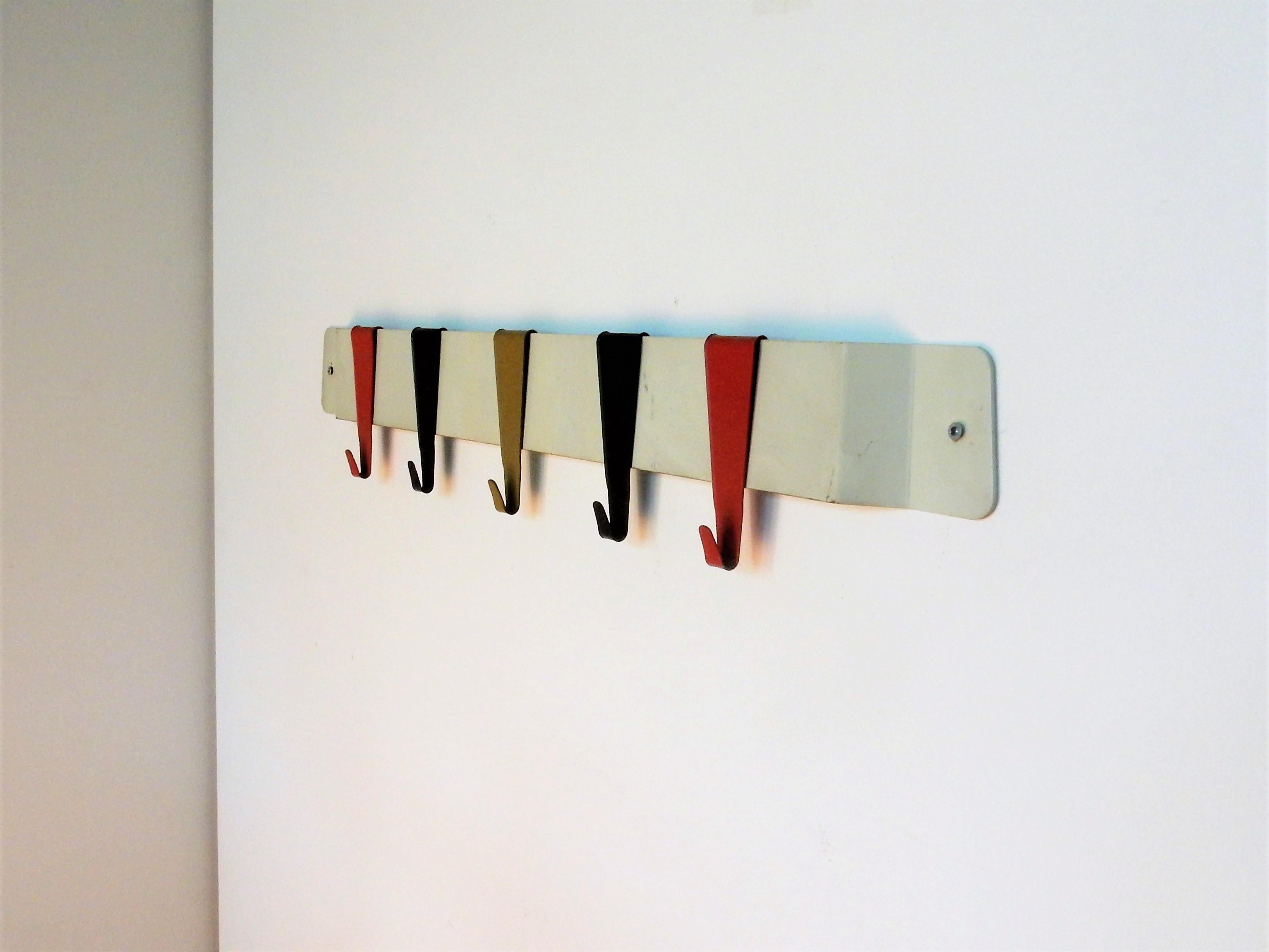 This small and elegant coat rack was mostly used as a children’s coat rack. It is a rack not often seen. It has a Minimalist white metal frame and five multicolored metal hooks. It is in a very good condition with some signs of age and use.