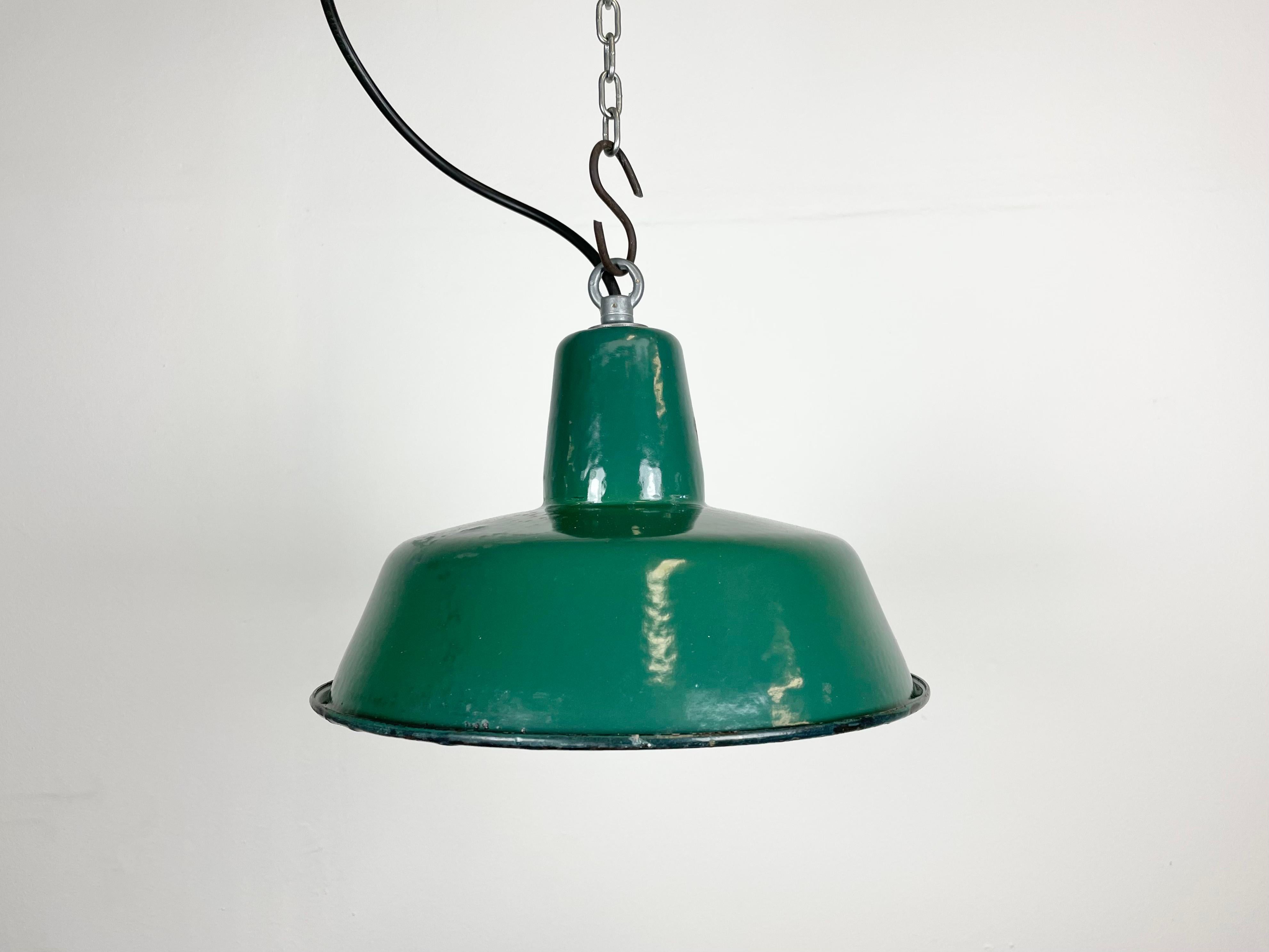 Lampada a sospensione industriale in smalto verde realizzata da Polam Wilkasy in Polonia negli anni Sessanta. Smalto bianco all'interno del paralume. Top in ferro. L'attacco in porcellana richiede lampadine E 27. Un nuovo cavo. Completamente