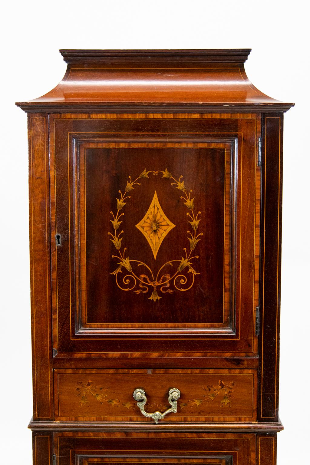 Small inlaid Mahogany Cabinet, is inlaid with boxwood and ebony stringing and bandings of bees wing satinwood. The center of the doors are inlaid with stylized bellflower wreaths in diamond shaped fans. The secondary wood is solid mahogany. The