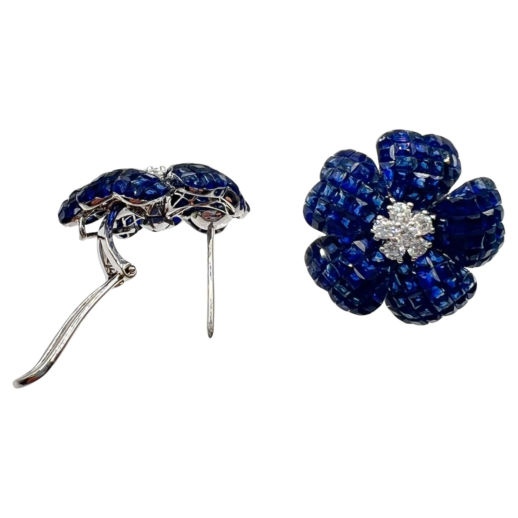 Flower stud earrings, designed as an invisibly-set calibre-cut sapphire flowerhead centering a round brilliant-cut diamond. Handcrafted in polished 18k white gold. Sapphires weighing 12.50 total carats. Two diamonds weighing 0.20 total carats. Posts