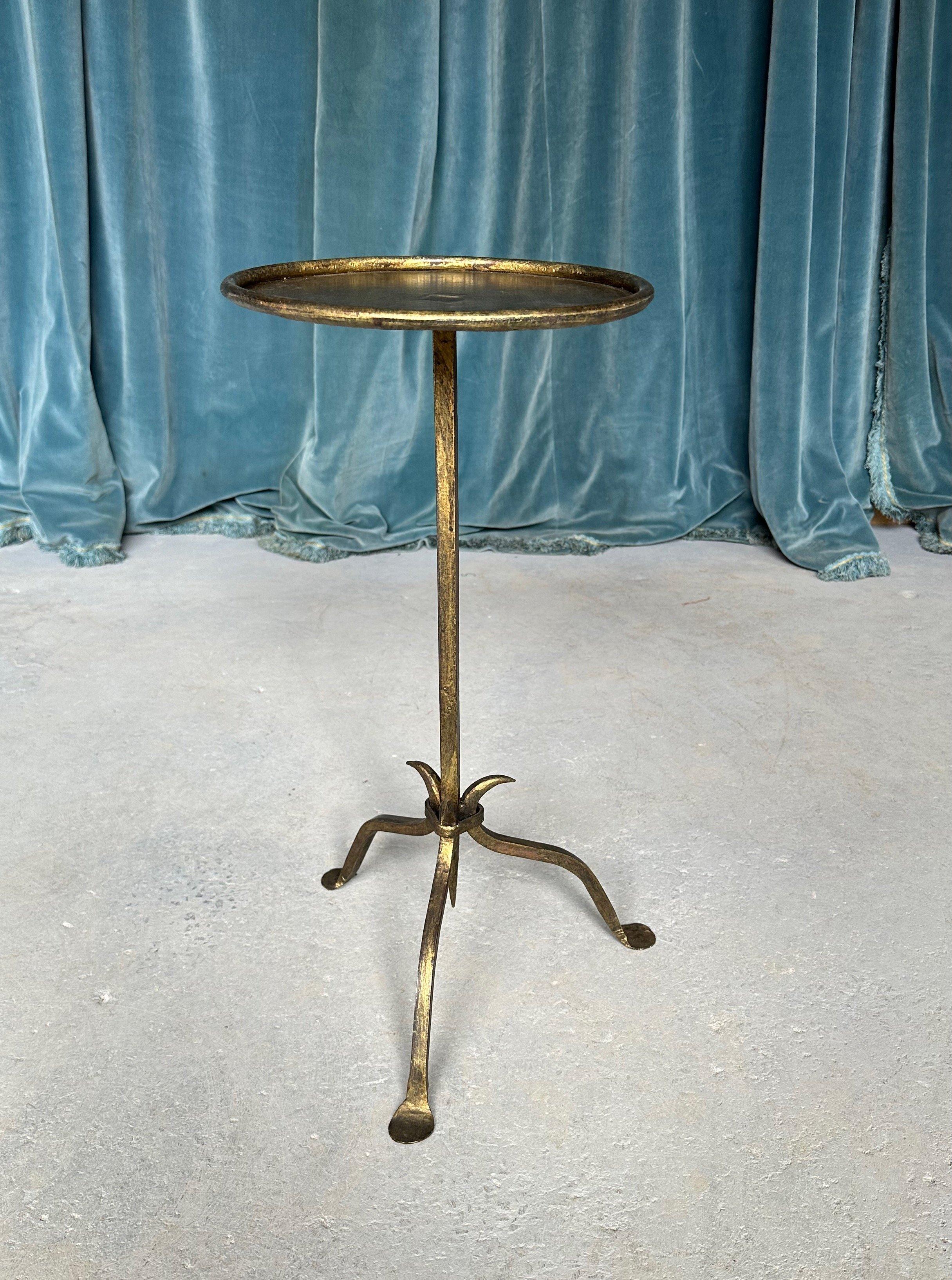 This recently fabricated Spanish iron side table features a distinctive design with a central stem that tapers to a fine point, attached to a tripod base that comprises three subtly curved legs. A rolled frame encircles the round top, providing a