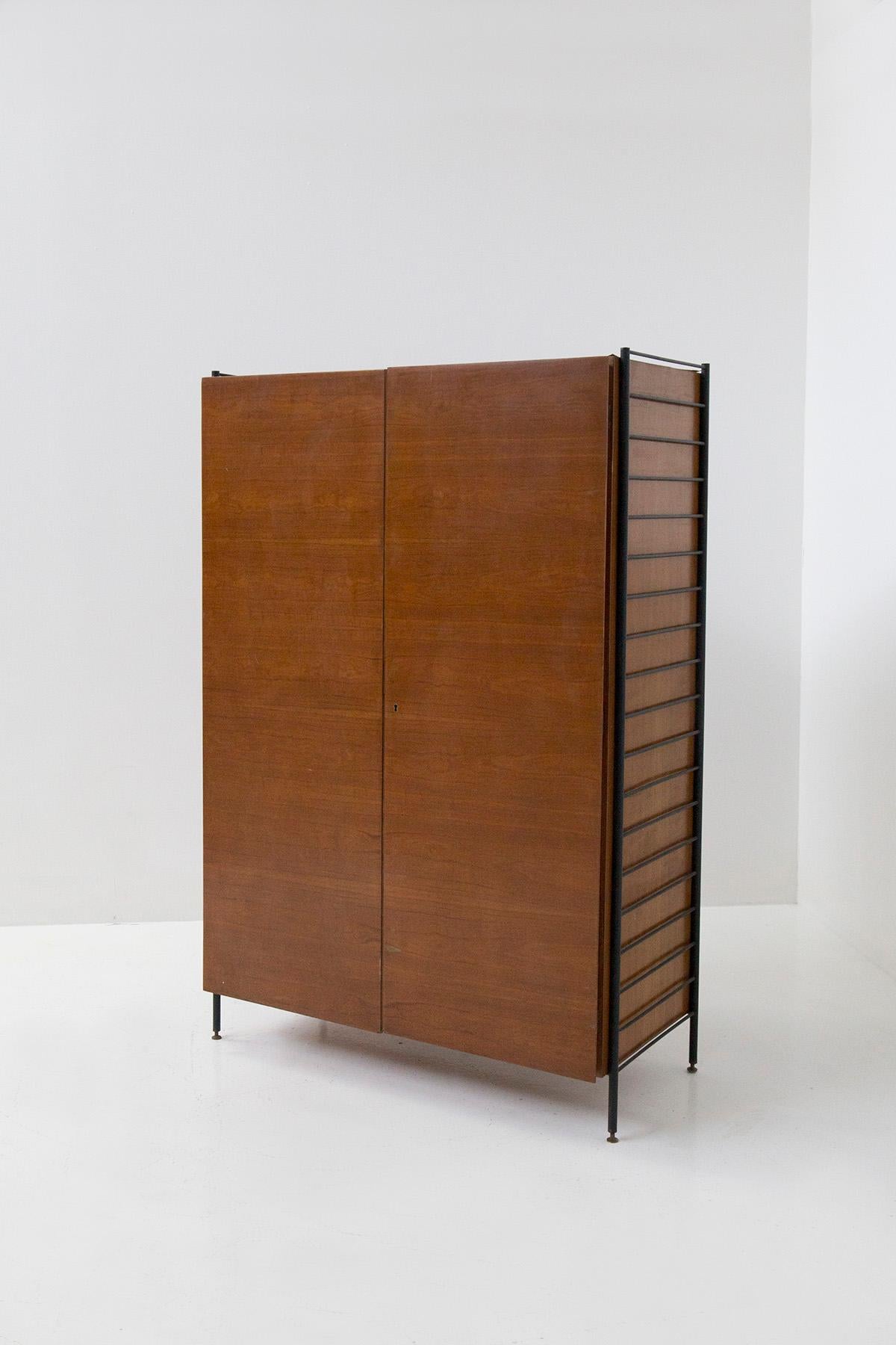 Small Italian bedroom wardrobe in wood and iron from the 1950s. The small wardrobe is made of wood with two hinged doors. On the sides of the wardrobe we find two iron ladders anchored to it, which serve as decoration but also as clothes and