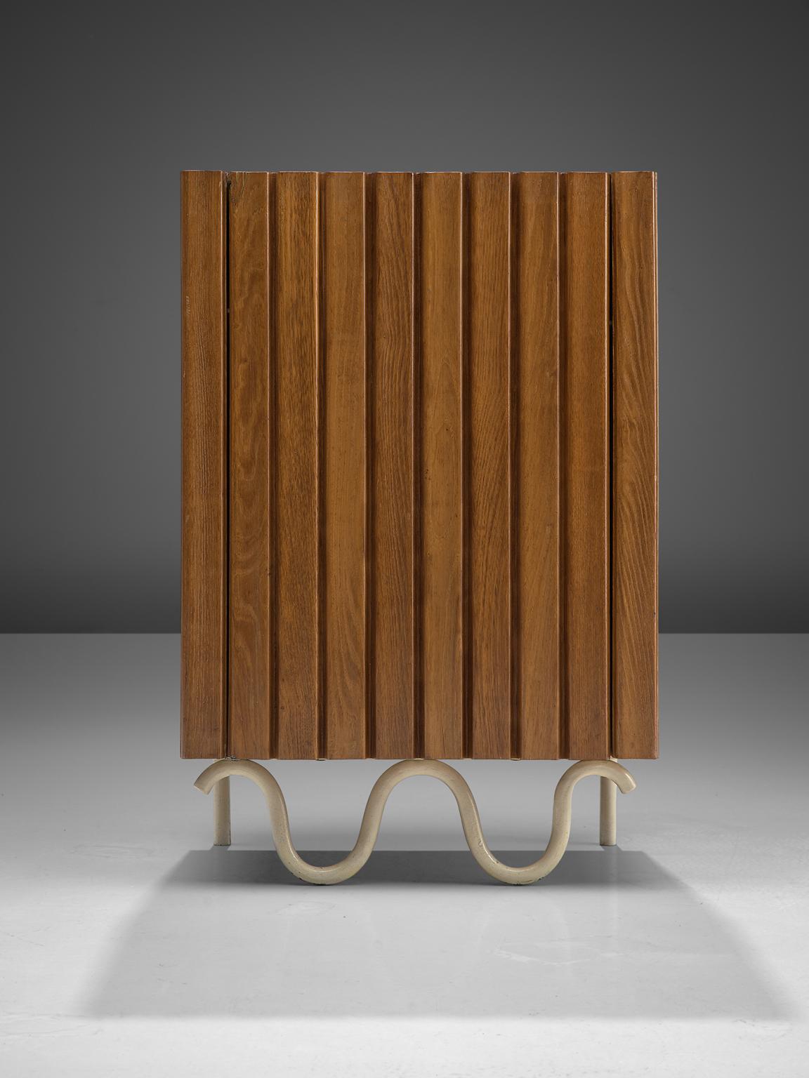 Italian cabinet, walnut, metal, Italy, 1950s.

Playful Italian walnut sideboard with linear engraved lines in the door. Most remarkable detail of this piece is of course the sinusoidal waves in lacquered metal underneath, forming the base of the