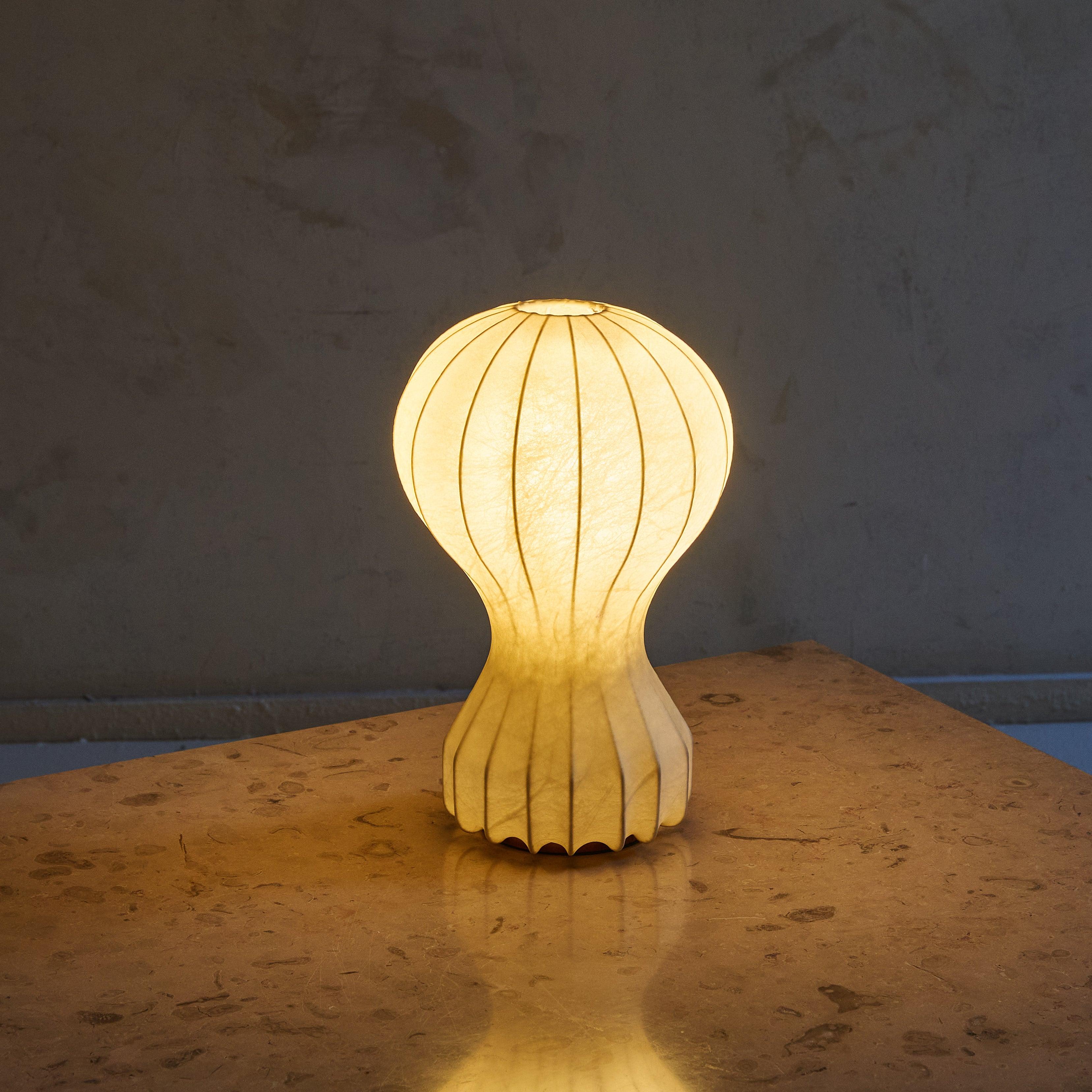 A 1960s Italian ‘Gatto’ table lamp designed by Achille & Pier Giacomo Castiglioni for Flos. This sculptural fixture features an enameled steel frame with a “cocoon” sprayed resin shade that mimics the look of goatskin parchment, emitting an ambient