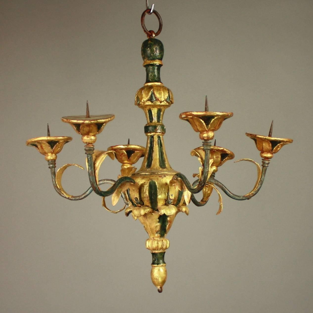 A small Italian painted and parcel-gilt chandelier. The baluster shaped stem fluted and carved with acanthus leaves, issuing six wrought iron arms with with scrolled leaves and leavy finials, the whole painted in a muted dark green and watergilded.