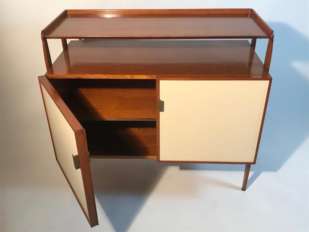 Small Italian wooden sideboard from the 60s. 
The central body is supported by four lateral legs which form an upper shelf. Brass handles and feet. The doors are covered with ivory-colored Formica.