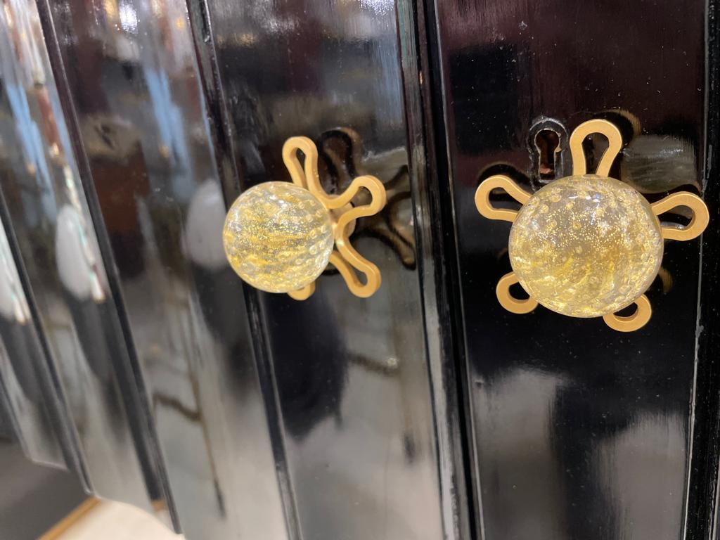 An original small Italian sideboard in ebonised wood. The handles are in Murano glass with gold inclusion attributed to Barovier & Toso. The sideboard has been repainted, top shows small scratches. Circa 1930s.