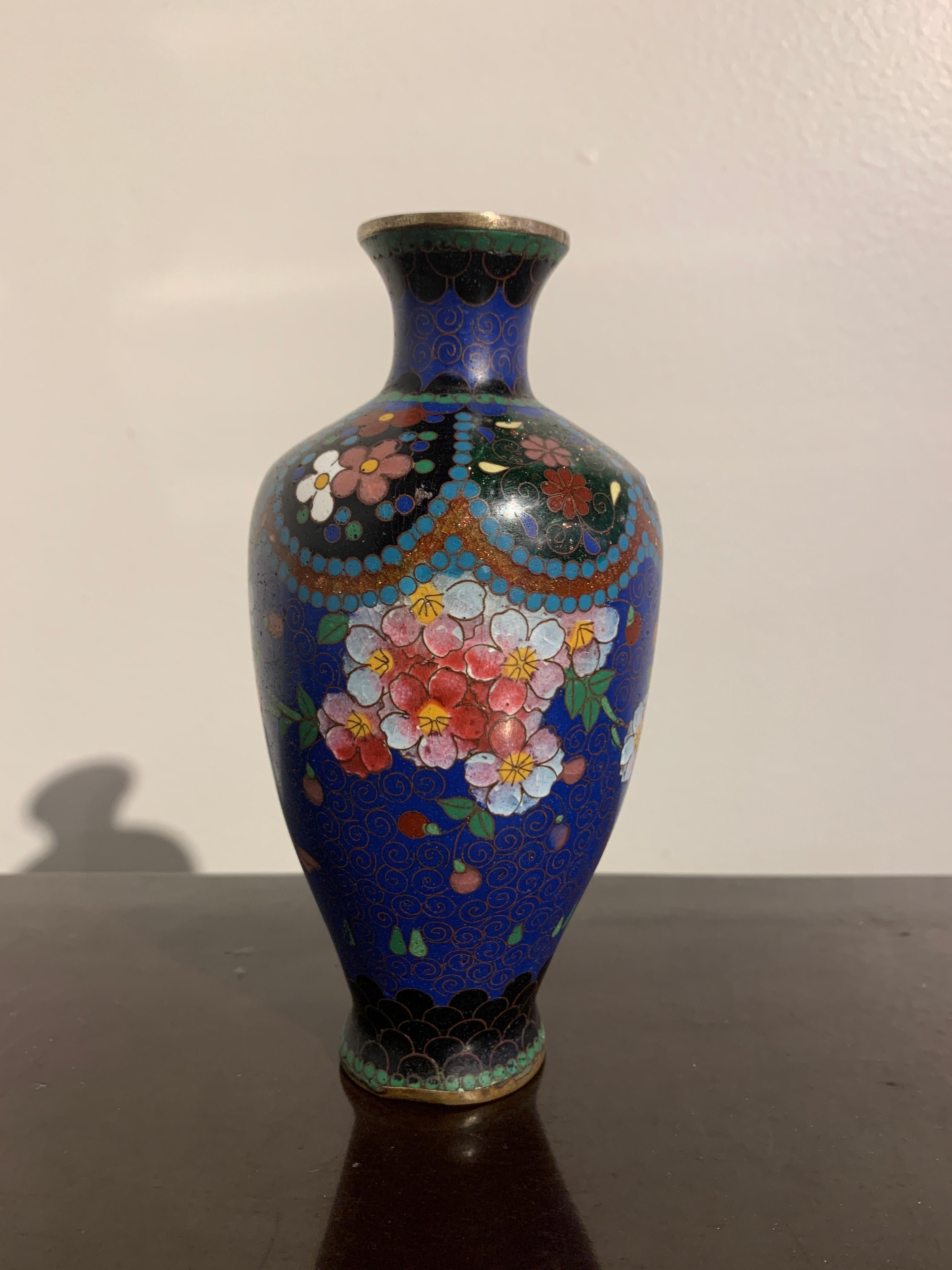 A lovely small Japanese blue ground cloisonné vase, Meiji period, early 20th century.

The vase of typical baluster form, with a blue ground body decorated with sprays of sakura, cherry blossoms. The blush colored blossoms in shades of pinks
