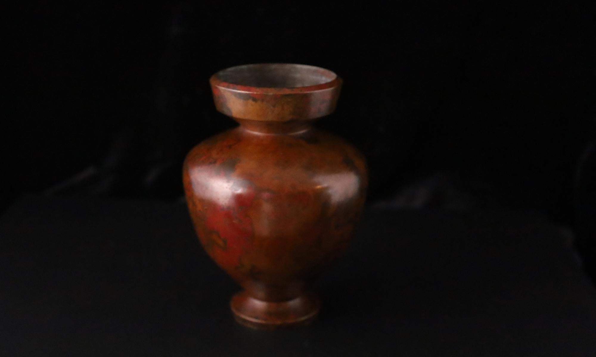 Questo vaso compatto in bronzo giapponese charme con la sua silhouette classica e la patina riccamente screziata nei toni caldi del marrone-rossastro. Le sottili variazioni della superficie evocano la bellezza organica del metallo consumato dal