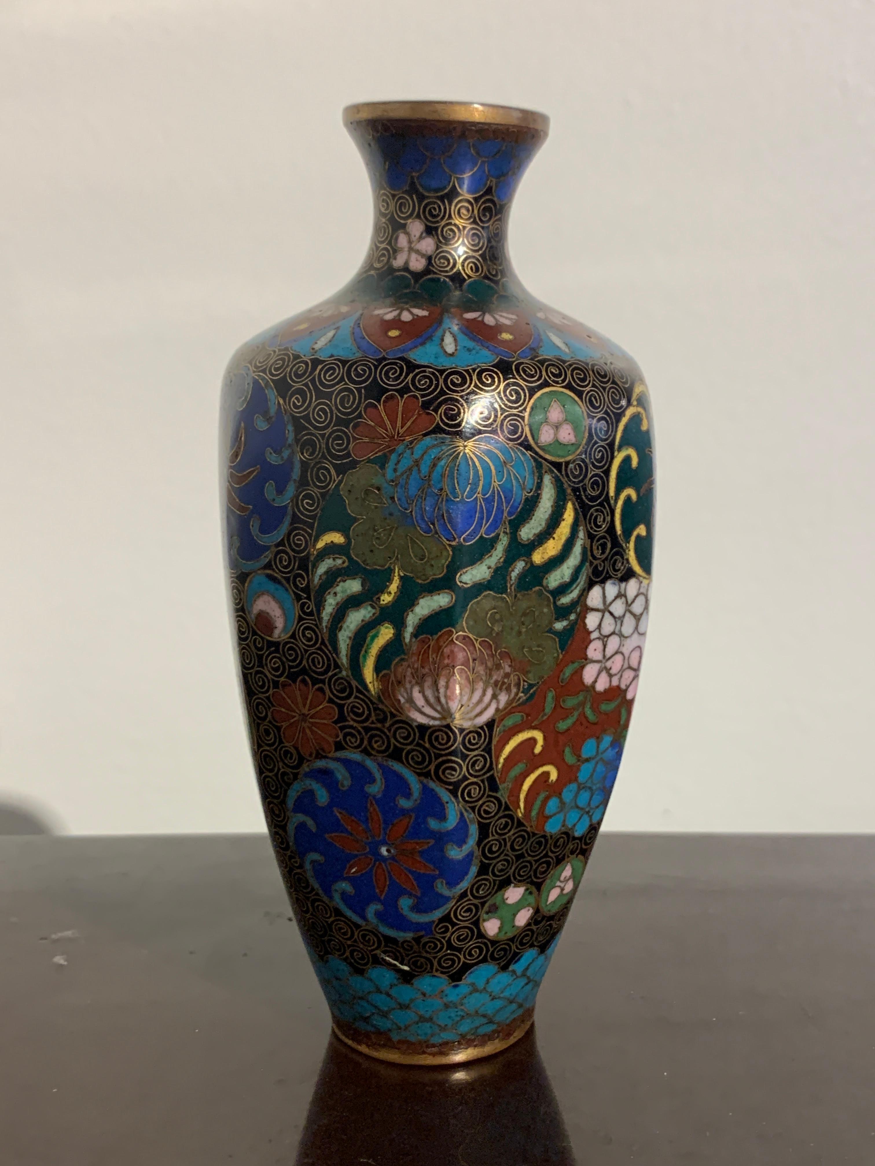 A fine and diminutive Japanese black ground cloisonné vase, Meiji period, late 19th century.

The small vase with six faceted sides. The black ground body of the vase decorated with various roundels, including four large ones depicting flowers
