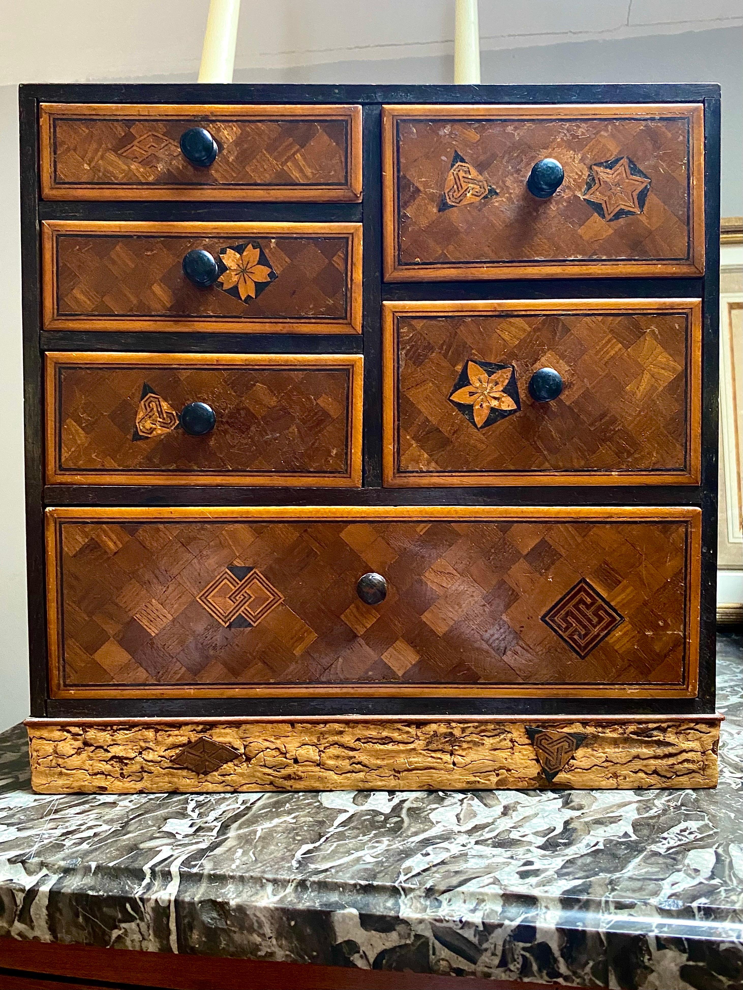 Very beautiful Japanese jewelry cabinet in Yosegi-zaiku marquetry composed of six drawers. The whole is inlaid with geometrically shaped pieces of wood and decorated with motifs resembling kamon (clan or Japanese family weapons). The leg of the