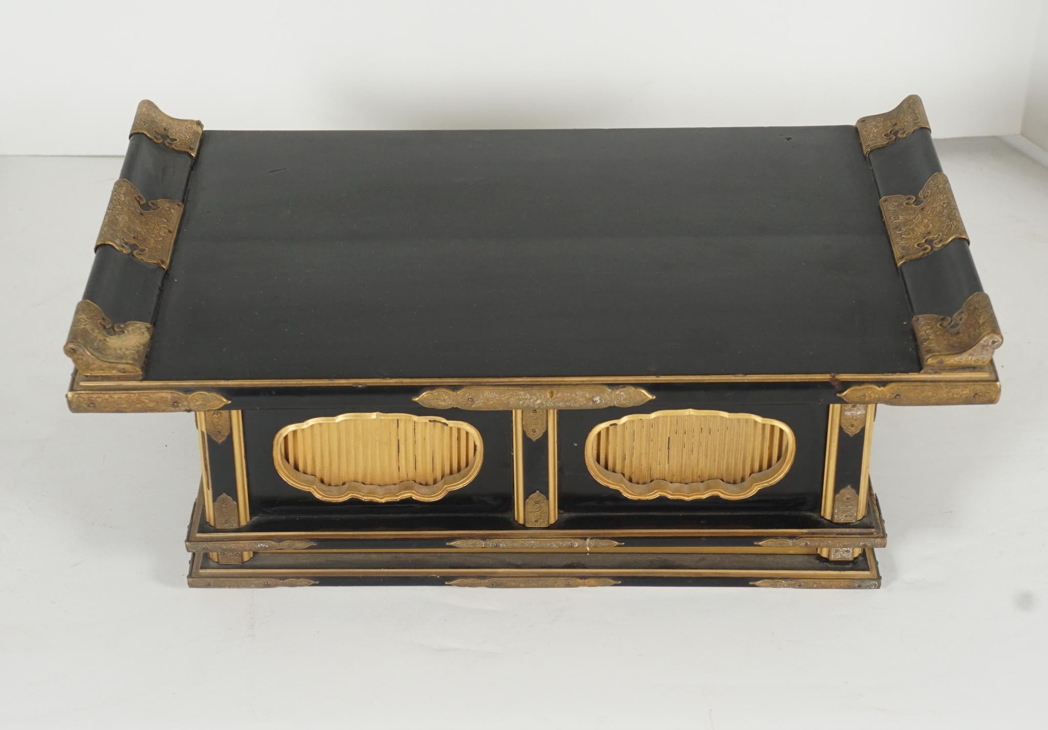 This small late 19th-century Meiji period altar or stand with gilded & engraved brass mounts is a refined example of the art of lacquer in Japan. Crafted of deep black shiny lacquer set out with simple gilded edges and rigged panels in gold lacquer
