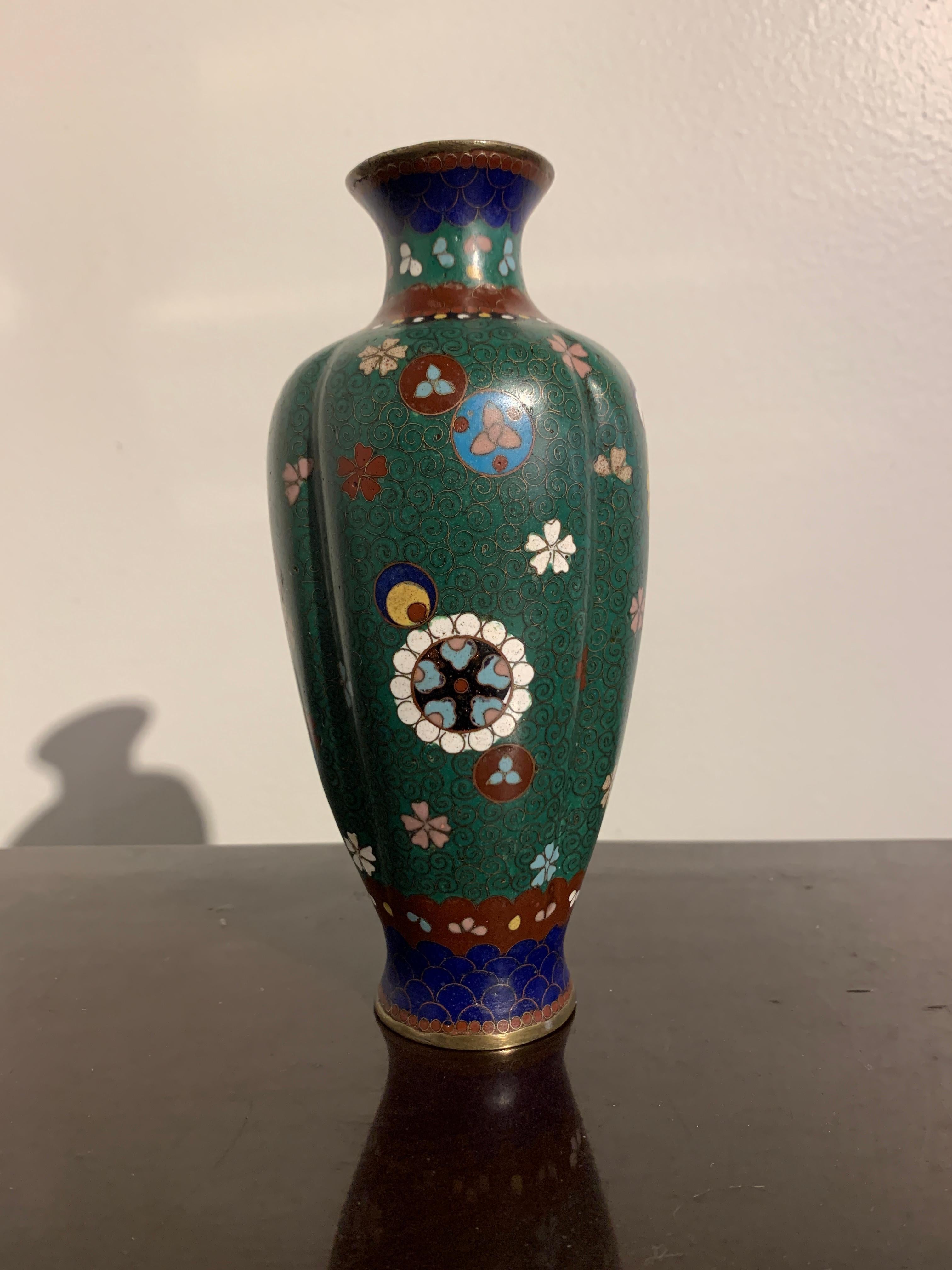 An elegant Japanese green ground cloisonné lobed vase, Meiji period, late 19th century, Japan.

The small vase of slender form, with a lobed melon shaped body. The green ground body decorated with various roundels of stylized mon and cherry