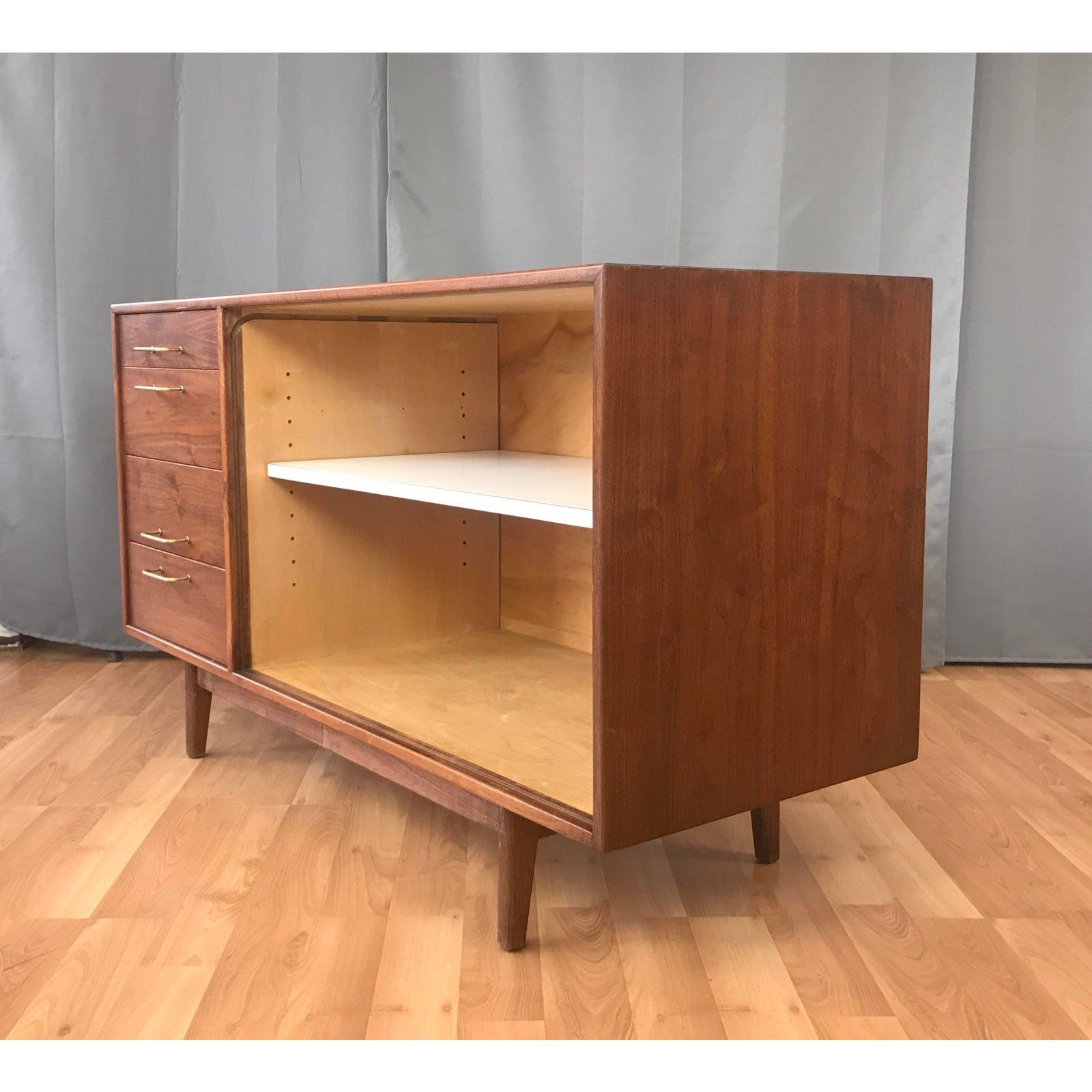 Jens Risom walnut credenza, this is a smaller size one, perfect for areas where you don't have all the room.
Four drawer with solid brass handles on it's left, right side has the large open shelving space with a large formica shelf.