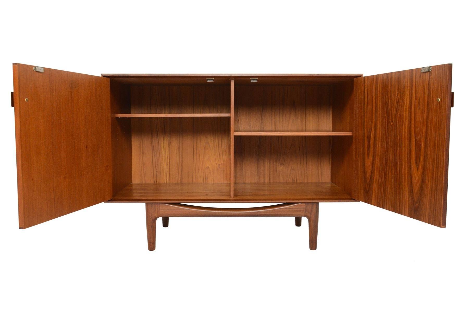 This small midcentury teak credenza was designed by Ib Kofod-Larsen for G Plan in 1961 for the Danish Range. Crafted in teak and afrormosia with handsomely refined lines, two wide doors open to reveal two bays with adjustable shelving. Finished on