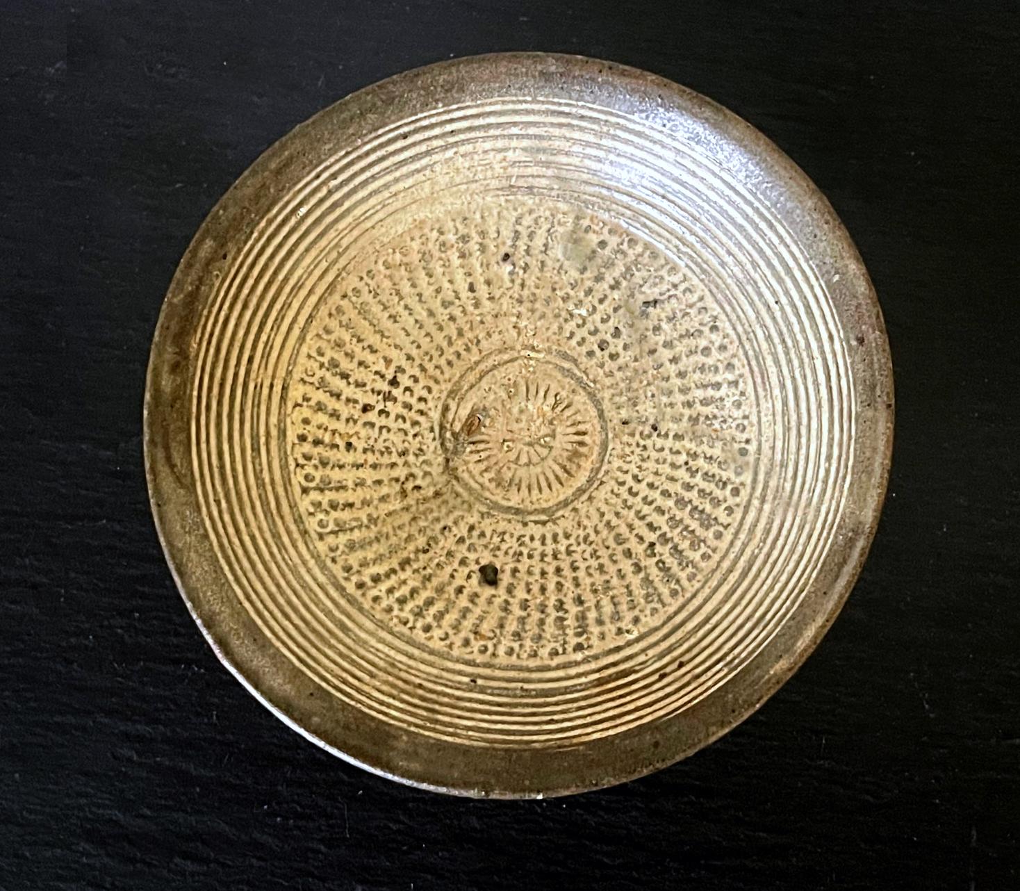 A small Korean ceramic shallow bowl on ringed foot in the classic Buncheong (or Punch'ong) style from Joseon Dynasty circa 15-16th century. Originally intended for wine-drinking likely, the bowl features a tight white slip decoration using stamping