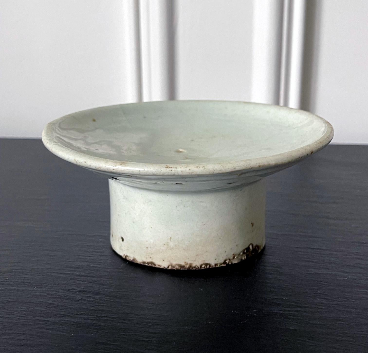 A ceramic dish with high cylindrical foot in white glaze from Korea, circa 19th century late Joseon Dynasty. By shape, this piece appears to be a ceremonial vessel that was used to make offerings on the altar. Although without inscription, we can't