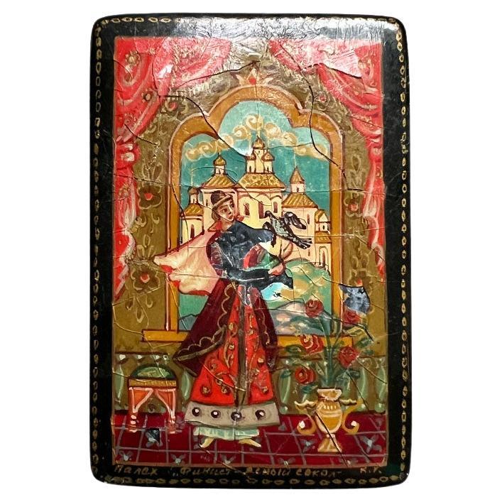 A small painted and lacquered box with a lid in black. This piece was created in the 1920s in the USSR. It is lacquered in a glossy black, with a hand-painted scene of a tzar on the top. The man seems to be holding a falcon, with a traditional