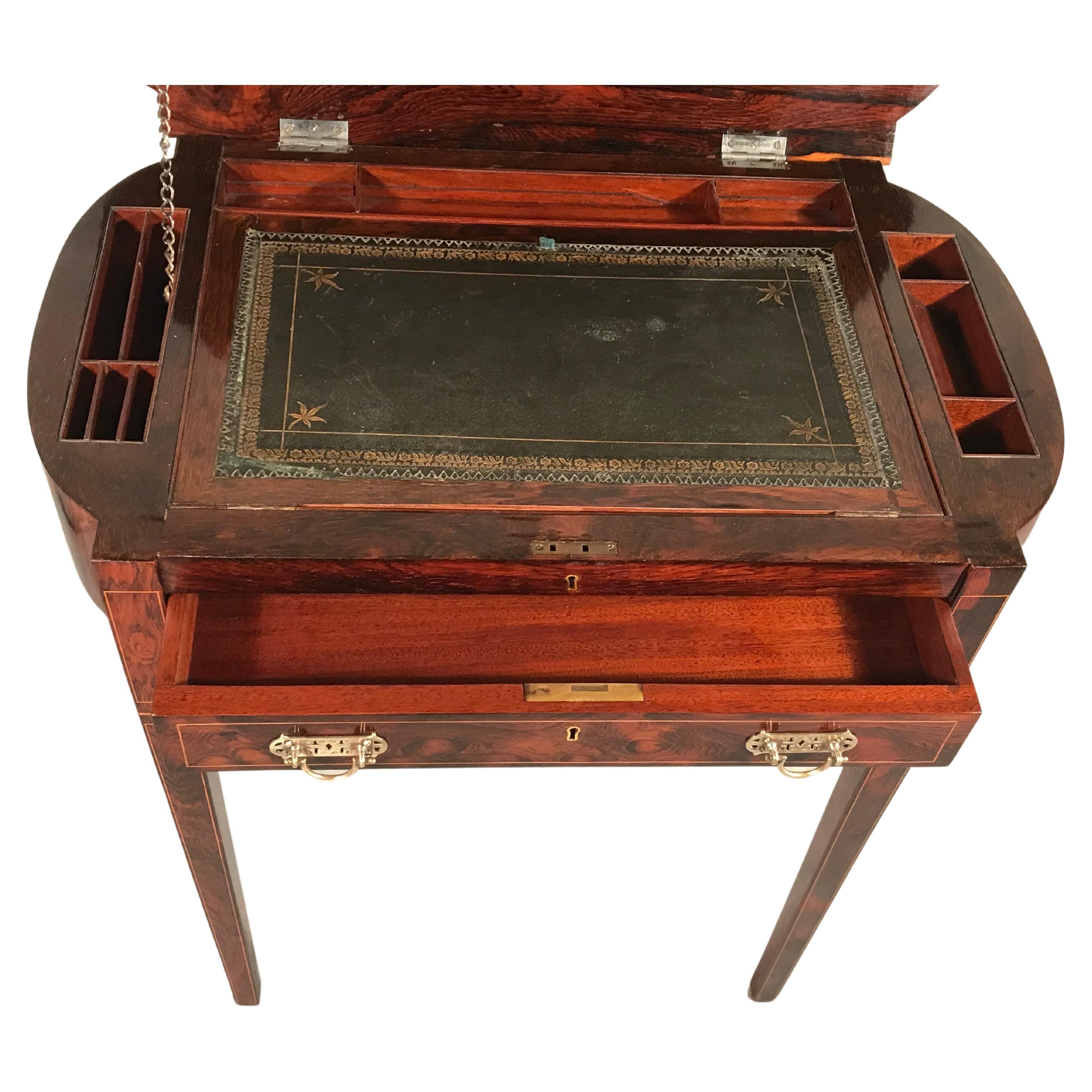This beautiful small lady's desk comes from England and was made during the Regency period around 1830. The desk features a pretty kingwood veneer on the outside. It has a flip up top which reveals a writing surface surrounded by small compartments
