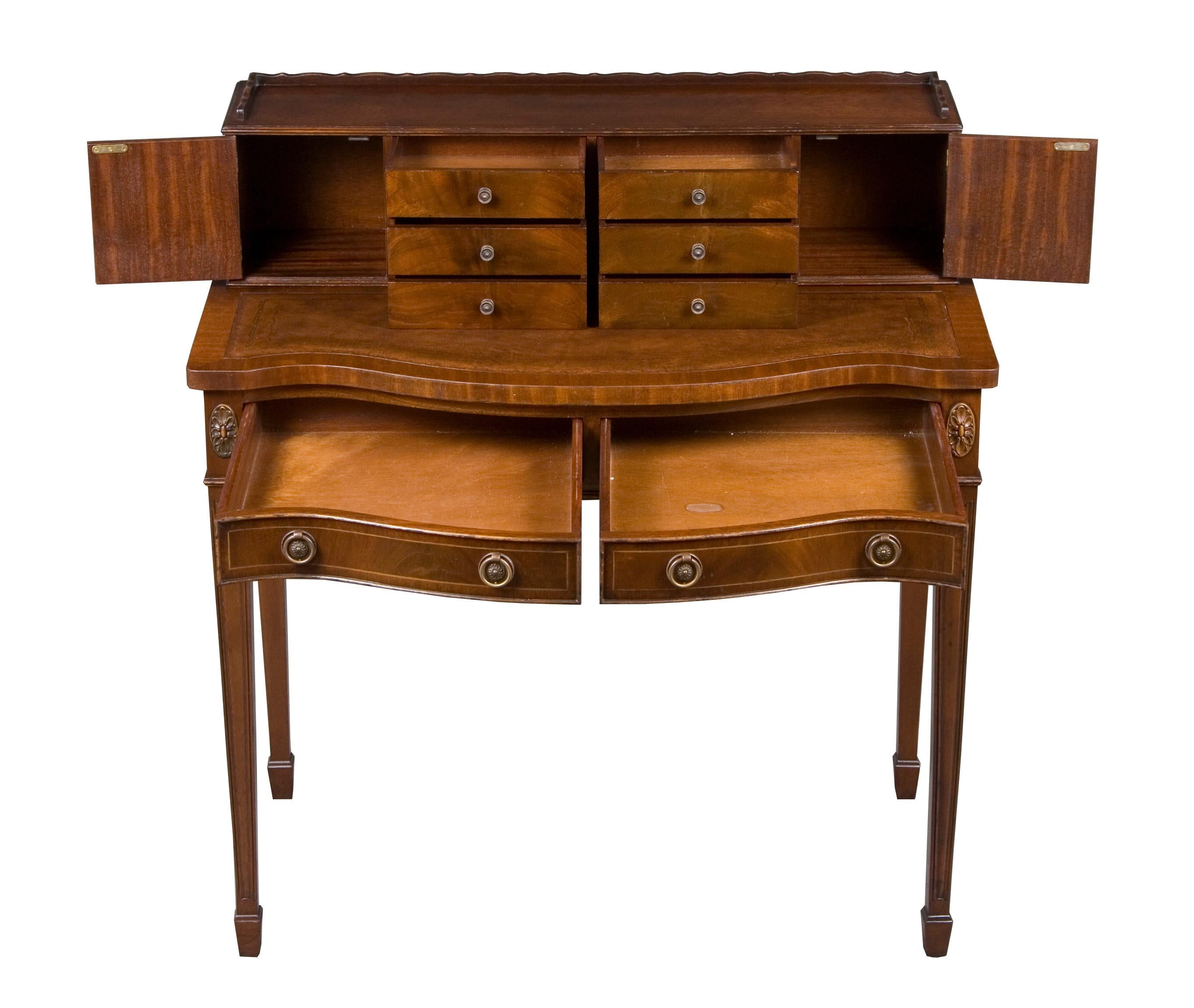 This quaint leather top writing desk has a bank of drawers and small cabinets on top providing great storage in a small space. With tapered legs, carved decorations, and antiqued brass pulls, this desk is beautiful as well as