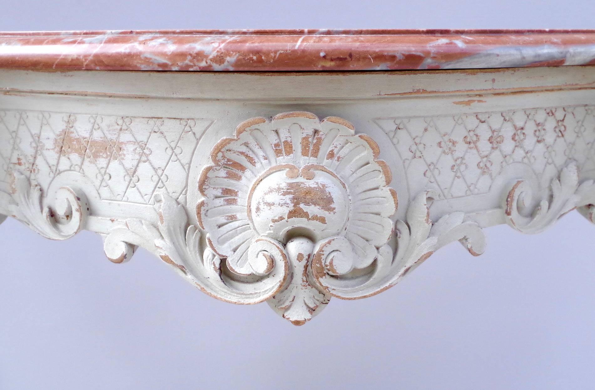 Small Louis XV style console in light grey. The apron is decorated with finely sculpted acanthus leaves and shells on a crisscross pattern background. The four curved legs are joined with a richly sculpted stretcher decorated with an openwork shell